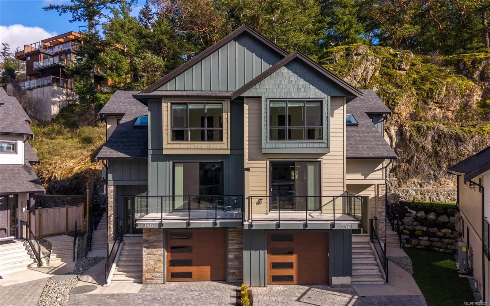 Duplex exterior home with garage doors, decks, and contemporary finishes.