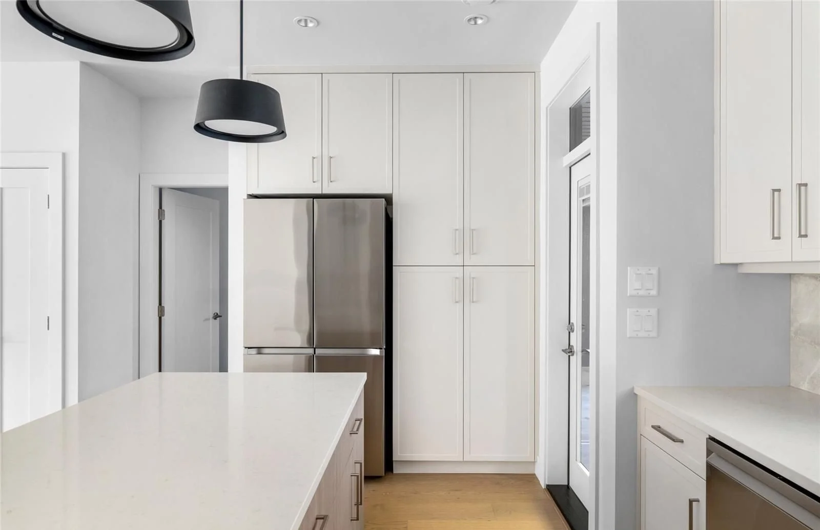 Custom build kitchen with white cabinets and stainless steel appliances.  Big kitchen island with white countertop. 