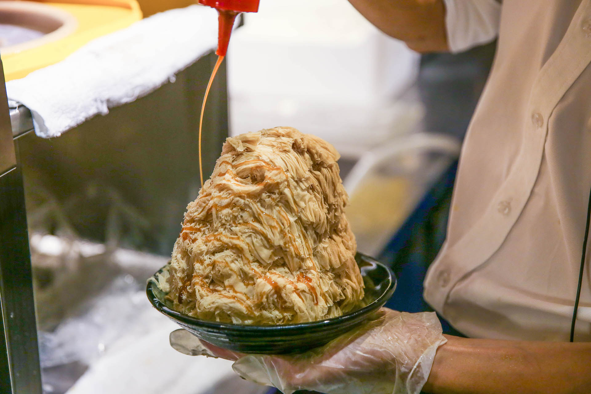 Ice Monster's Coffee Sweet Cotton Ice drizzled with caramel in slow motion.