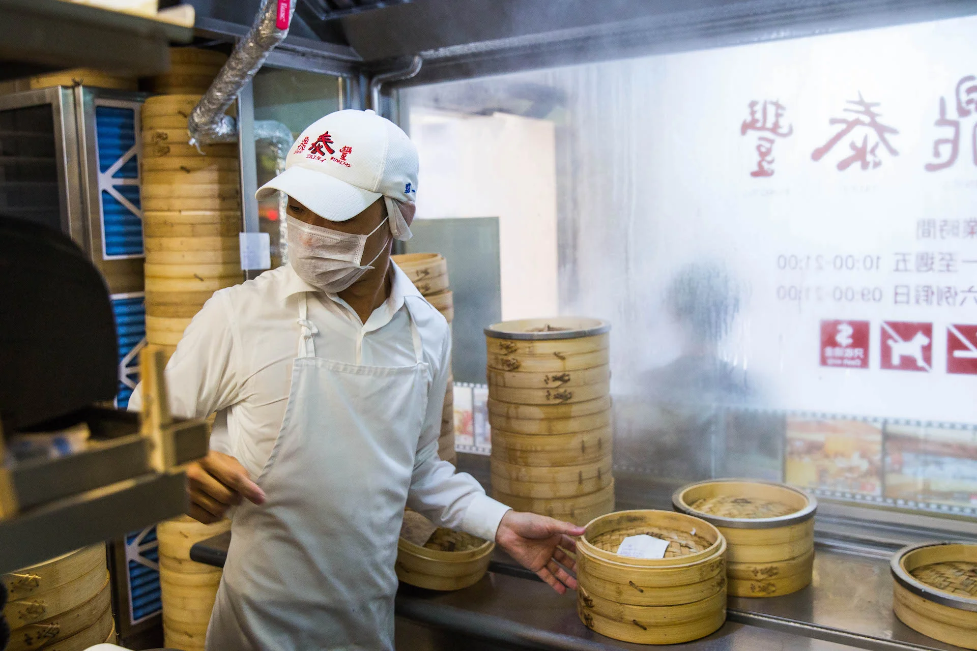 A chef quickly turns to check the orders while switching cooked and uncooked dumplings.