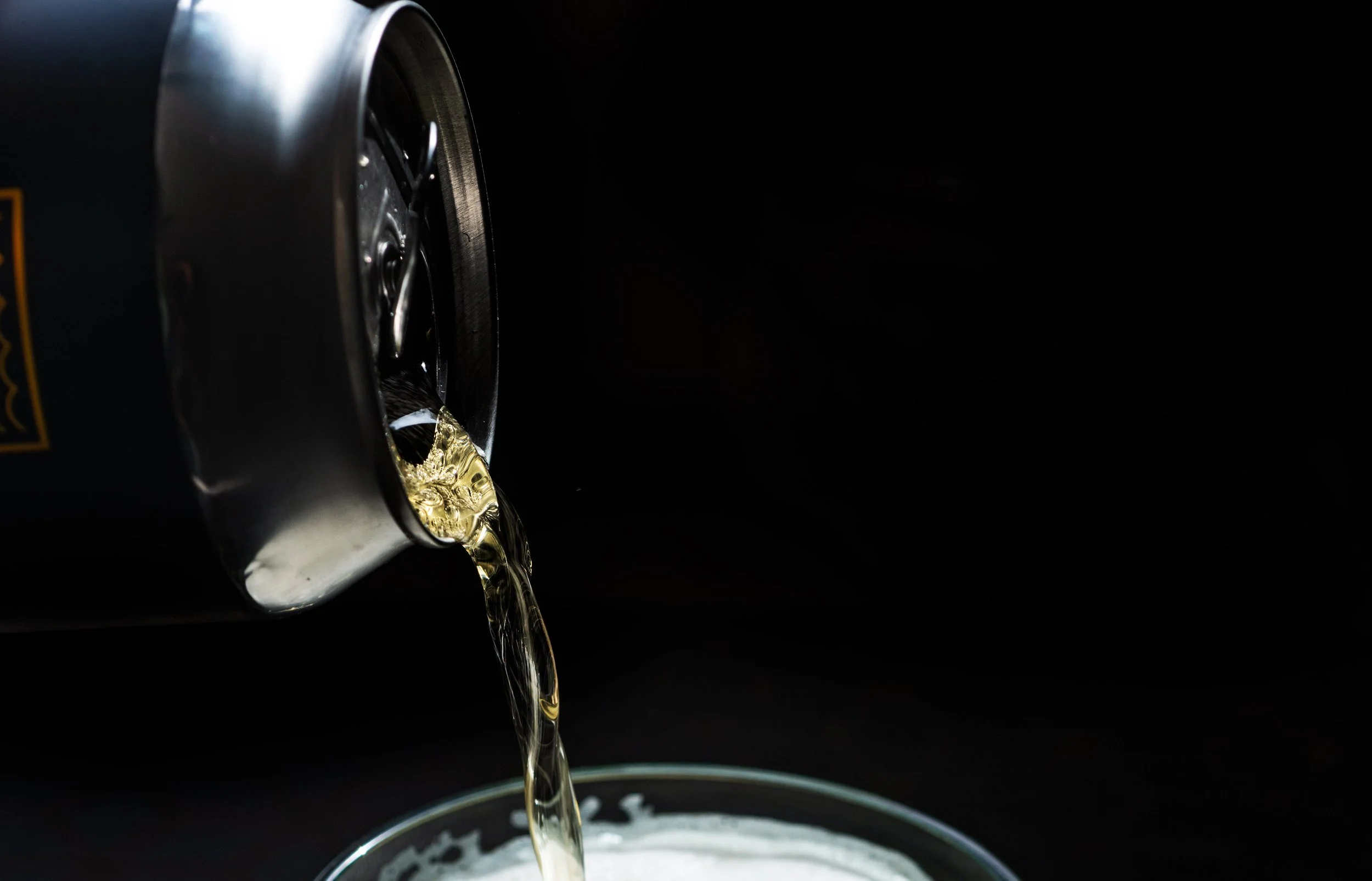 close-up-of-a-silver-can-pouring-golden-liquid.jpg