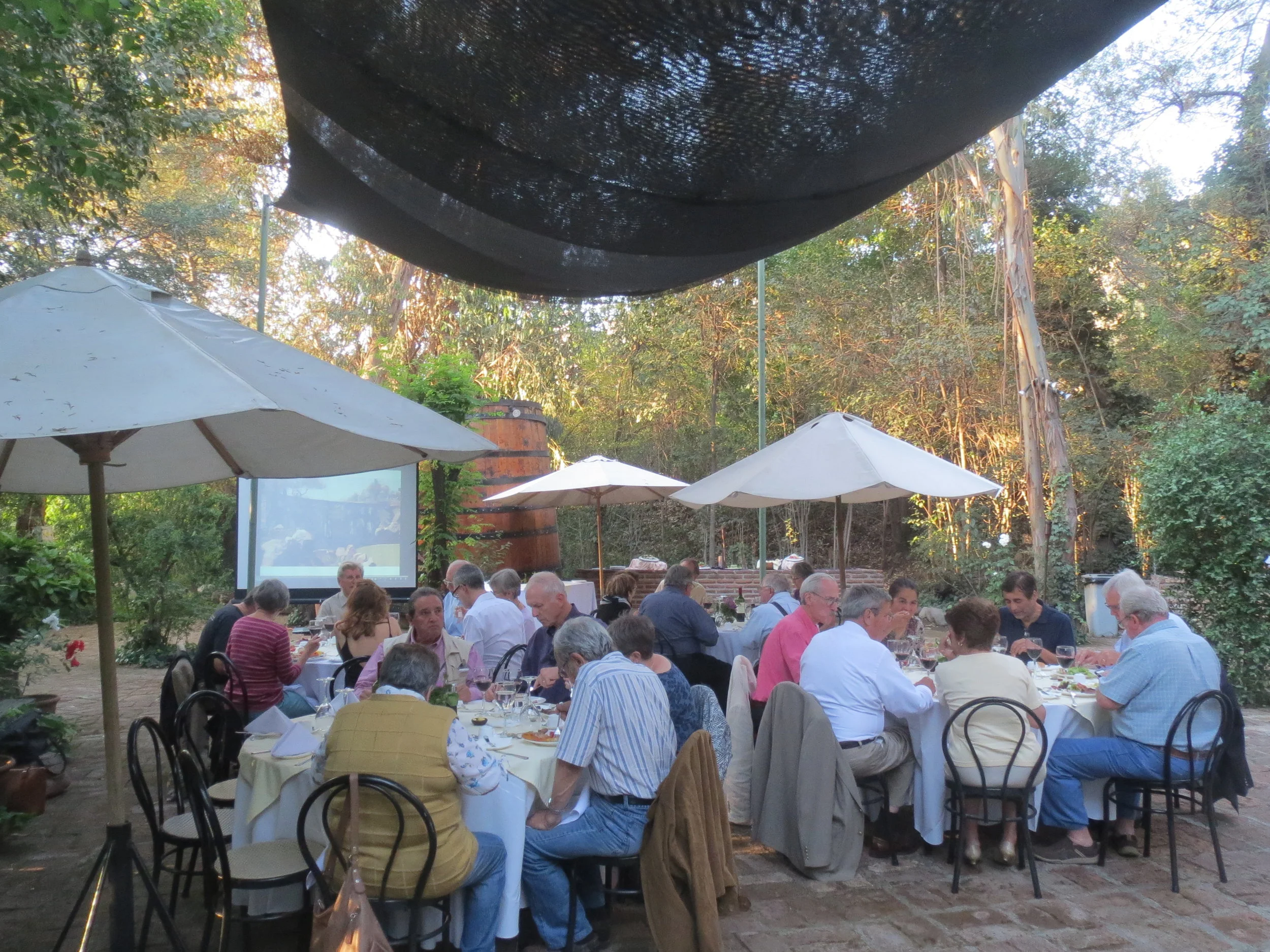 Chile Group 23 Reunion; asado front table Monica&Romano Buschizzo, David Campos, Carl&Pat McCrary,Karl Kindel's slides running in the background