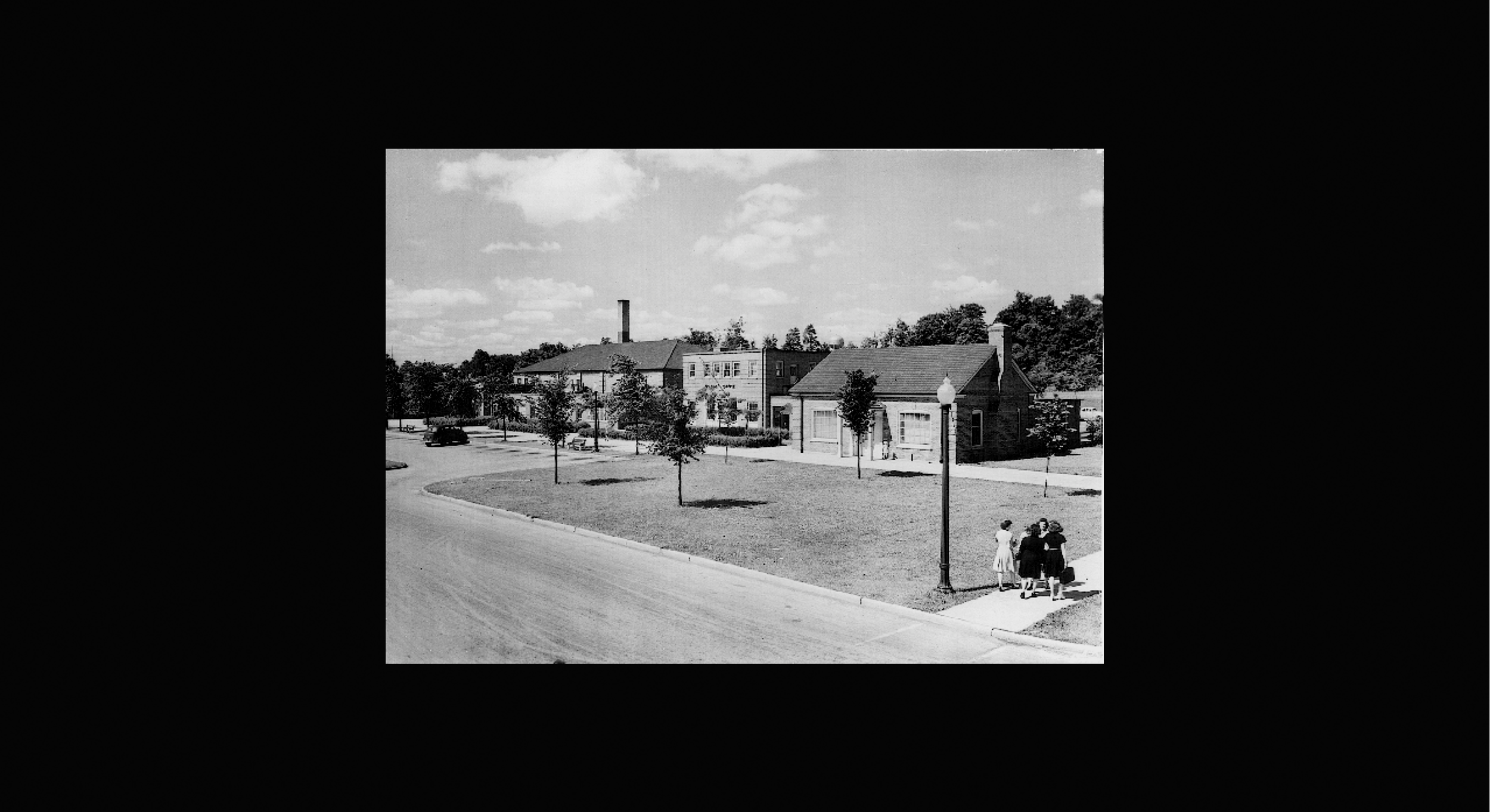   Slide (detail downtown):  This is part of downtown, showing the brick buildings, including the tavern and the stores: supermarket w/butcher, drug store, cinema, post office and others. 