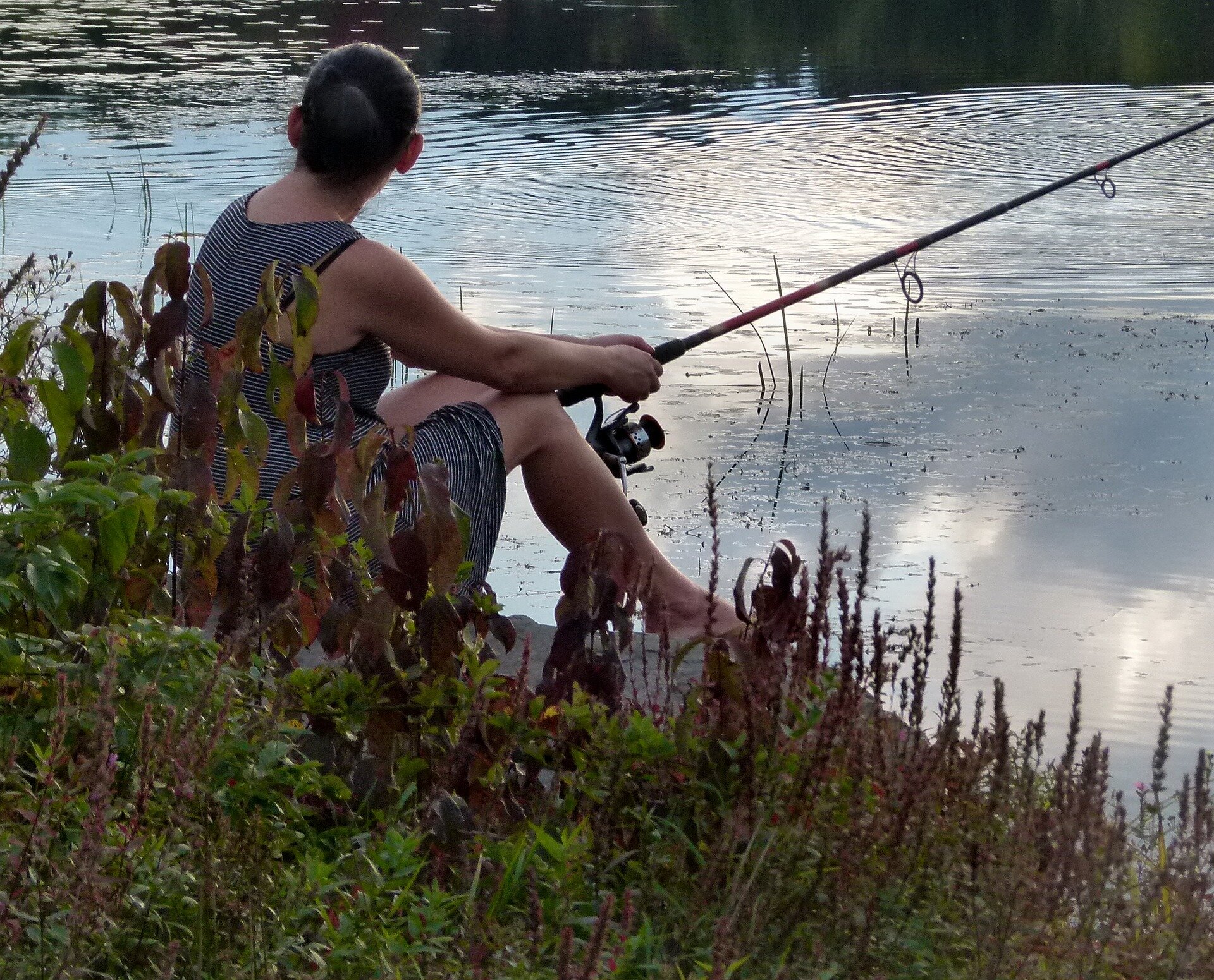 Здесь ловят рыбу. Рыбалка летом. Женщина с удочкой. Женщины на рыбалке. Девушка рыбачит.