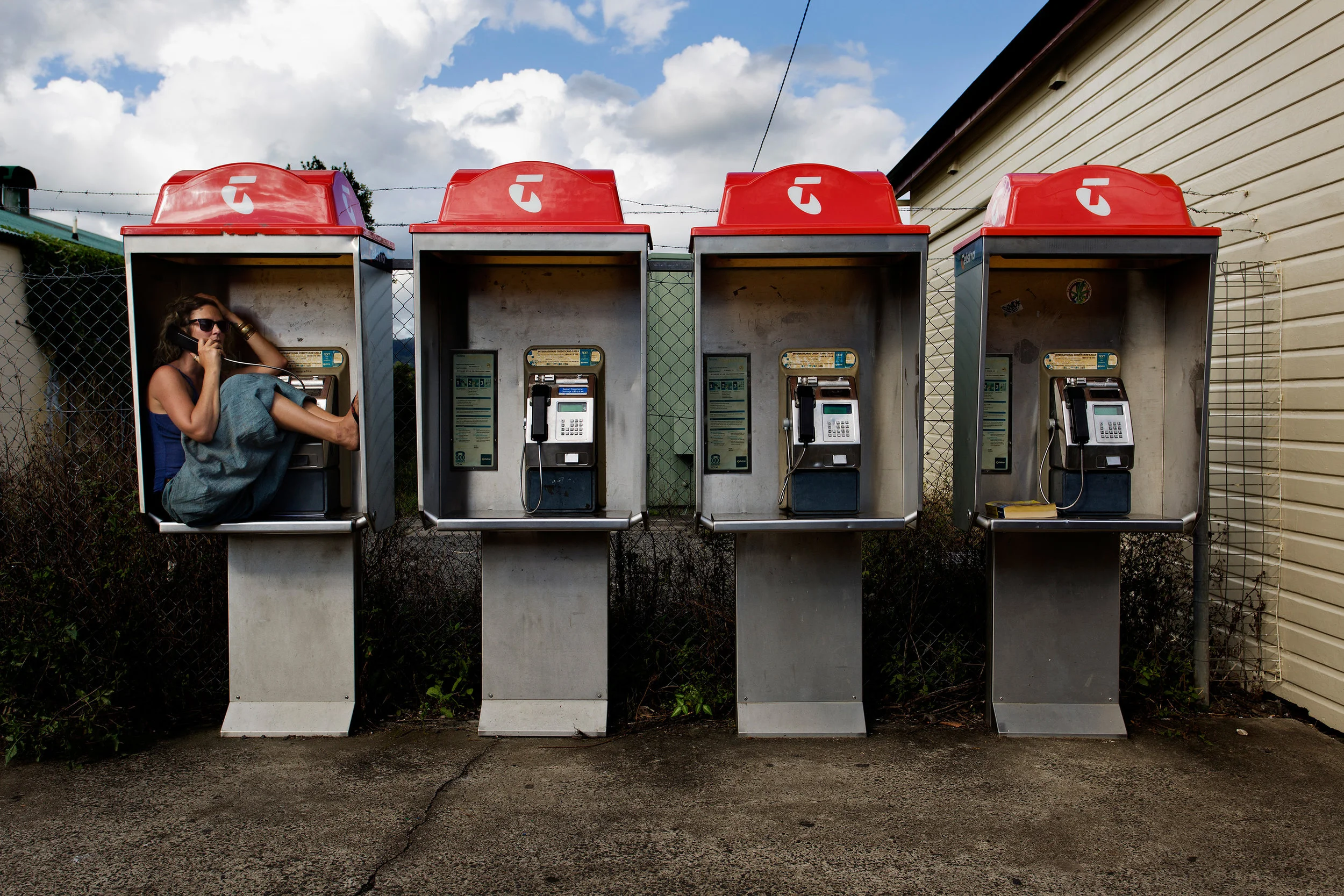  A young lady finds a comfortable seat in a phone booth on Cullen Street, Nimbin NSW, Australia. Mardigrass attracts thousands of tourists annually. 