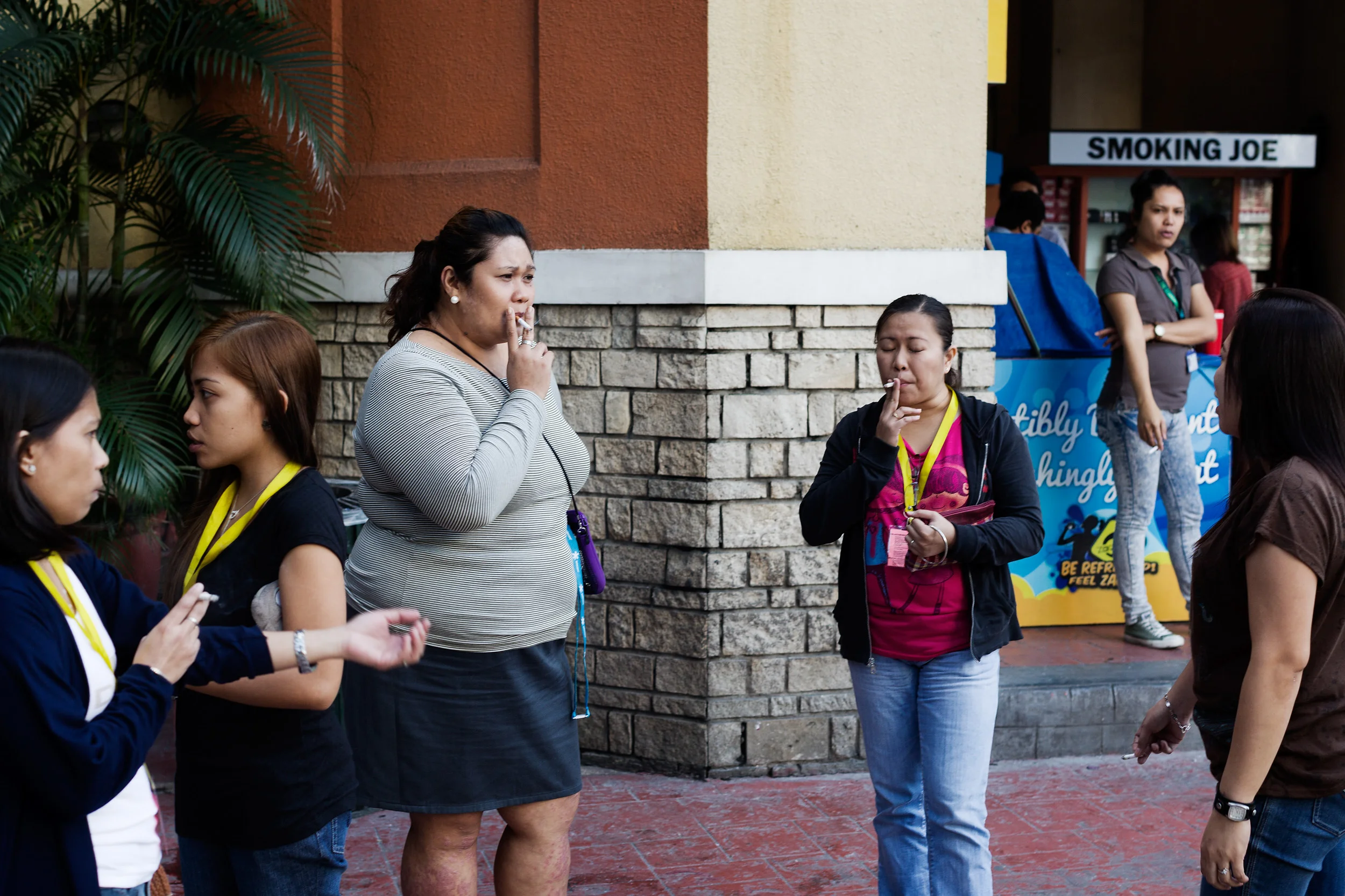  Call centre agents smoke cigarettes on their break from work in Eastwood City, a BPO-targeted area of Manila, Philippines. Export-orientated companies are offered tax breaks and incentives by establishing business in Eastwood City Cyberpark, which i
