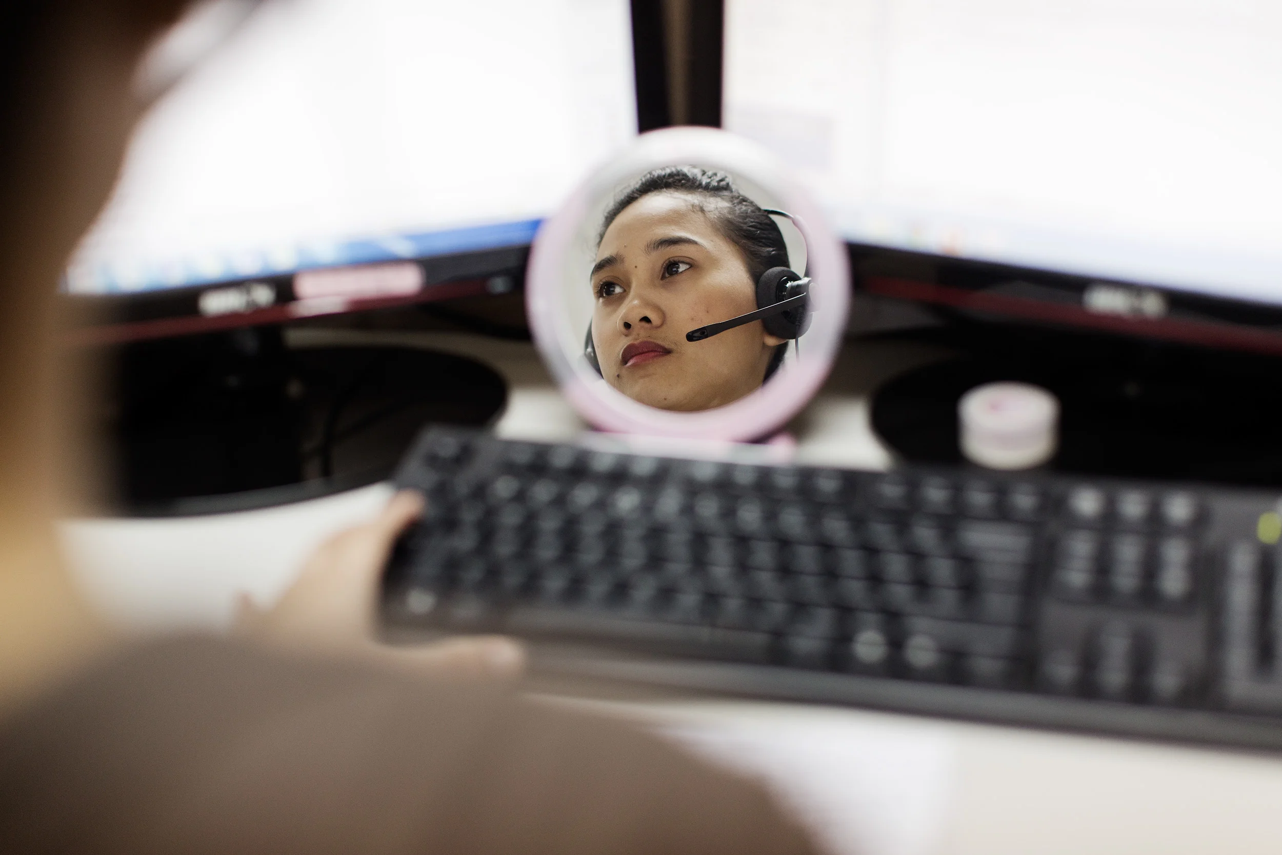  A call centre worker works into the early morning at Pinoy Partners Outsourcing Center in Makati City, Philippines. Some employees have mirrors on their desks which reminds them to smile whilst talking to customers. 