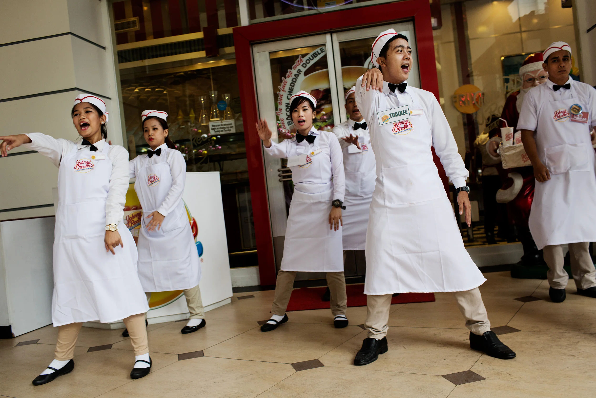  Employees of American owned Johnny Rockets in Eastwood City dance near the entrance of the restaurant attempting to draw customers from the street.  Eastwood City Mall is a lucrative business opportunity for foreign owned food chains and retail outl