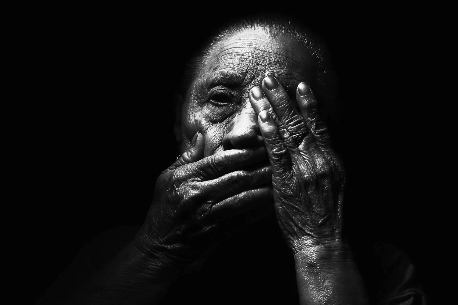 Hight contrast black and white portrait of a woman with hands over face