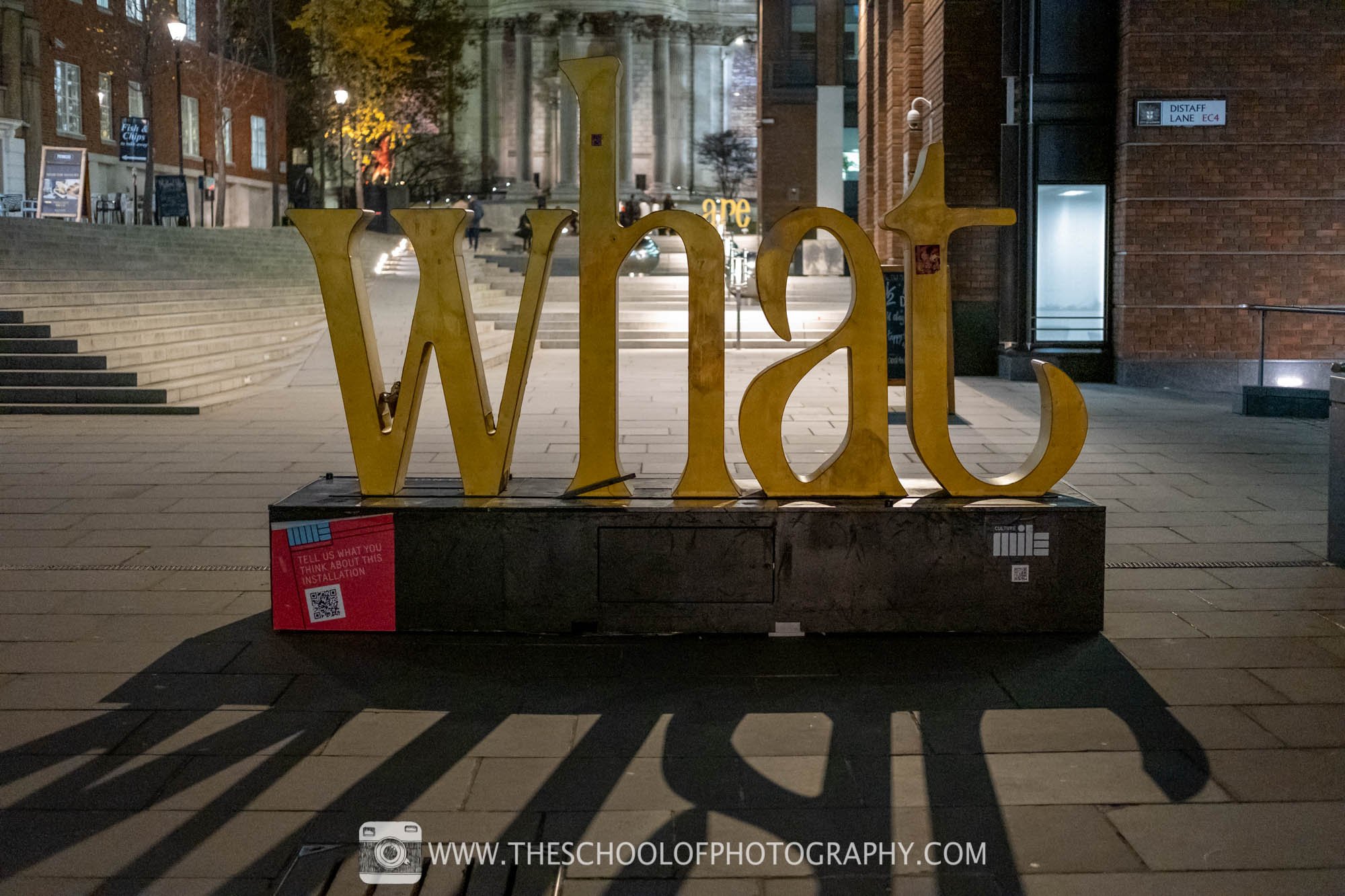 A sign spelling out the word 'What' using crop sensor camera