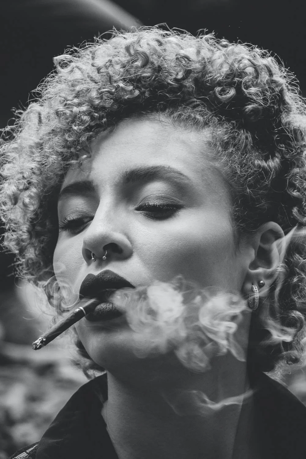 Low contrast black and white photo of woman smoking