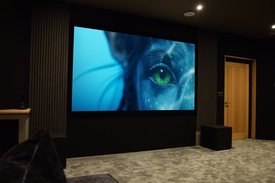 Large television screen displaying a close-up image of a person's eye with a blue background in a dark room.
