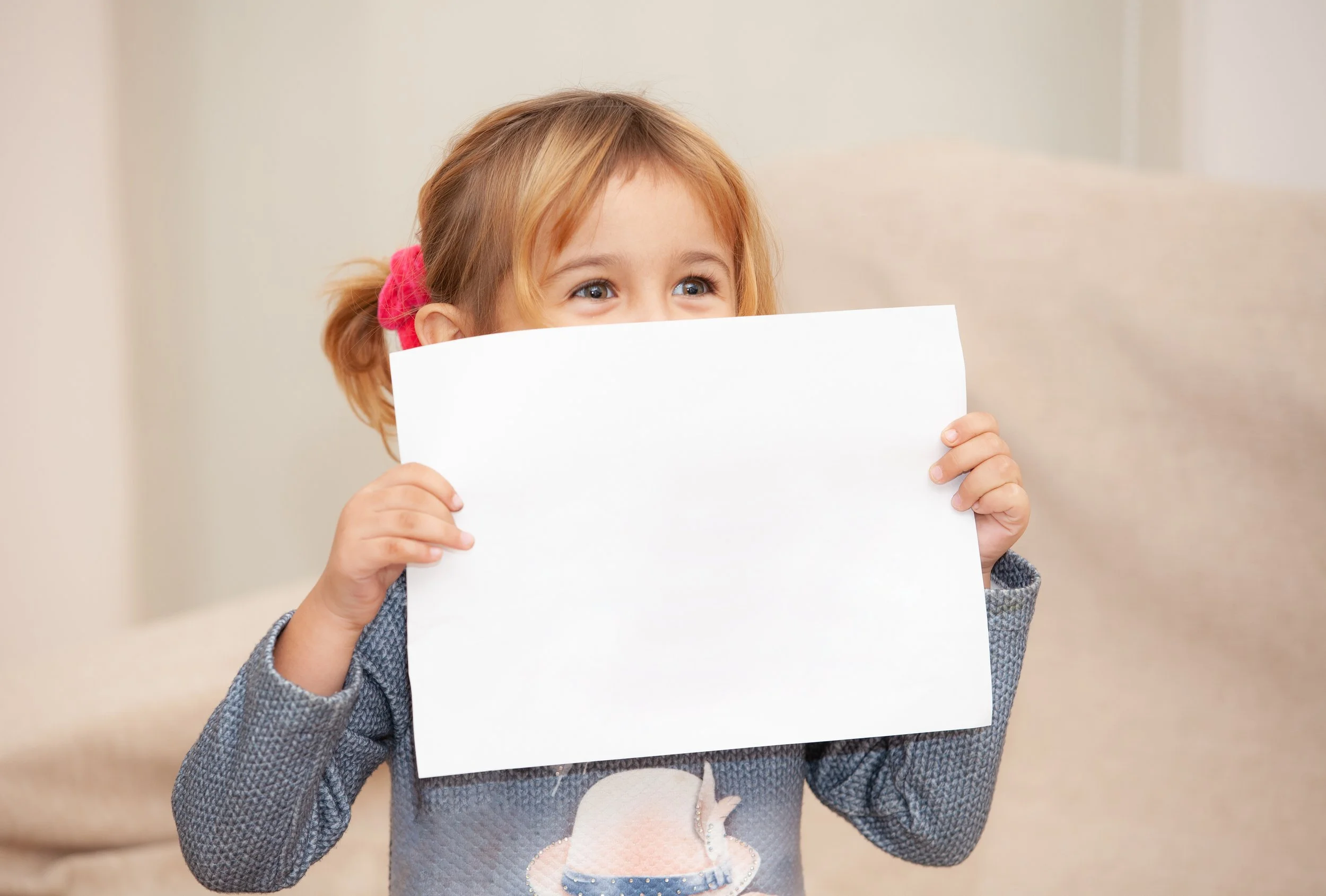 Child with blank paper in front of mouth