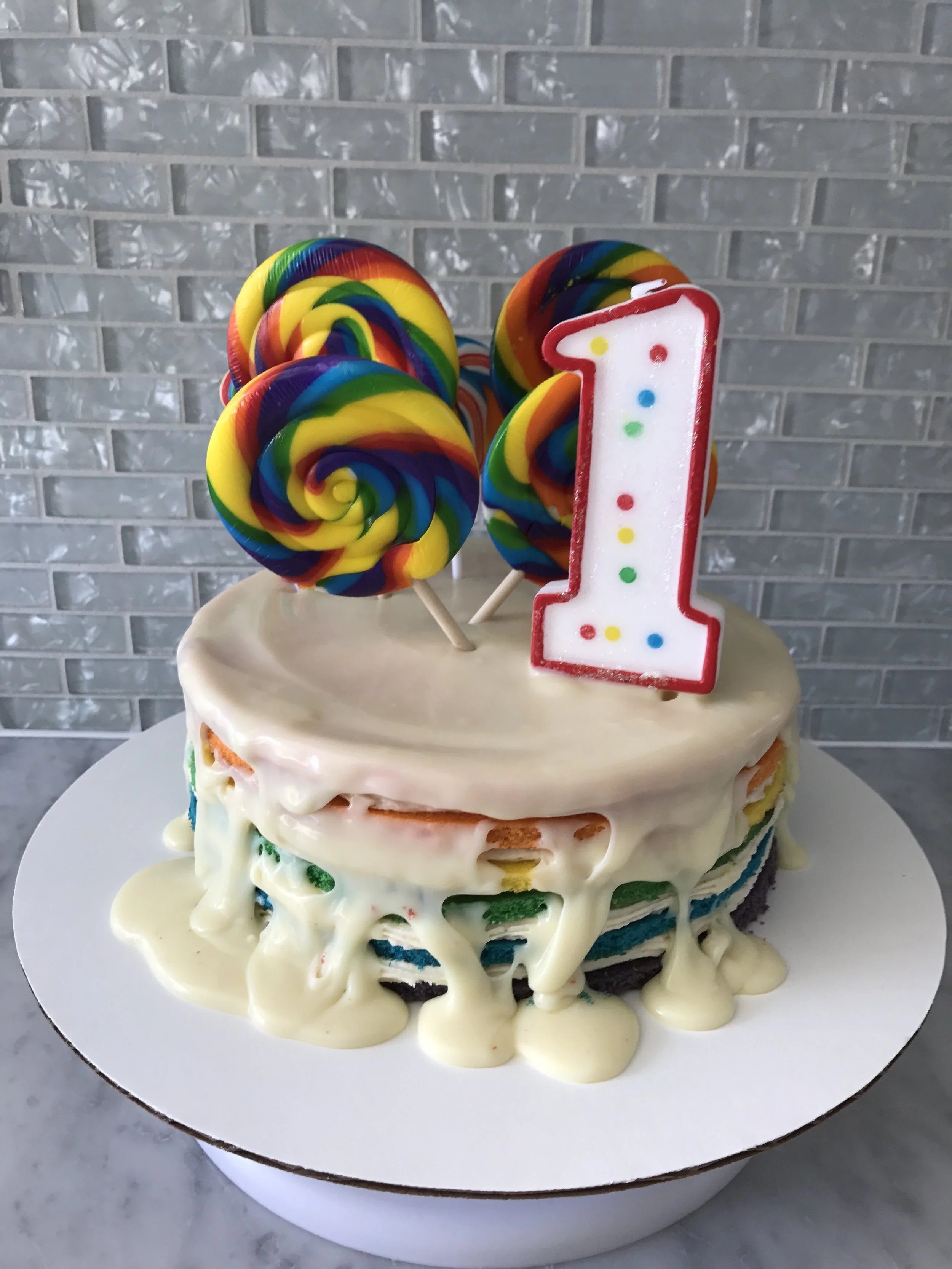 I am so incredibly pleased with how Amelia's cake turned out! This is a 6 layer vanilla rainbow cake with vanilla buttercream frosting between the layers, a white chocolate ganache drip on top and finished with some massive lollipops and her candle! 