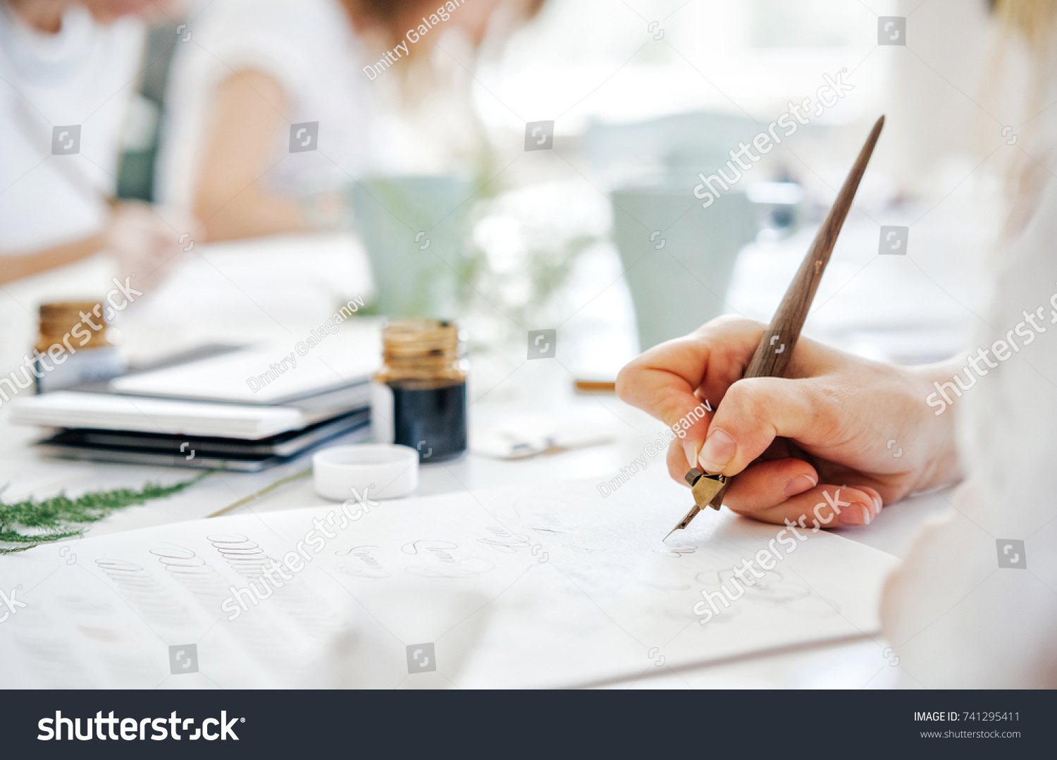 stock-photo-training-of-calligraphy-the-hand-of-a-girl-with-a-pen-writes-on-paper-with-ink-741295411.jpg