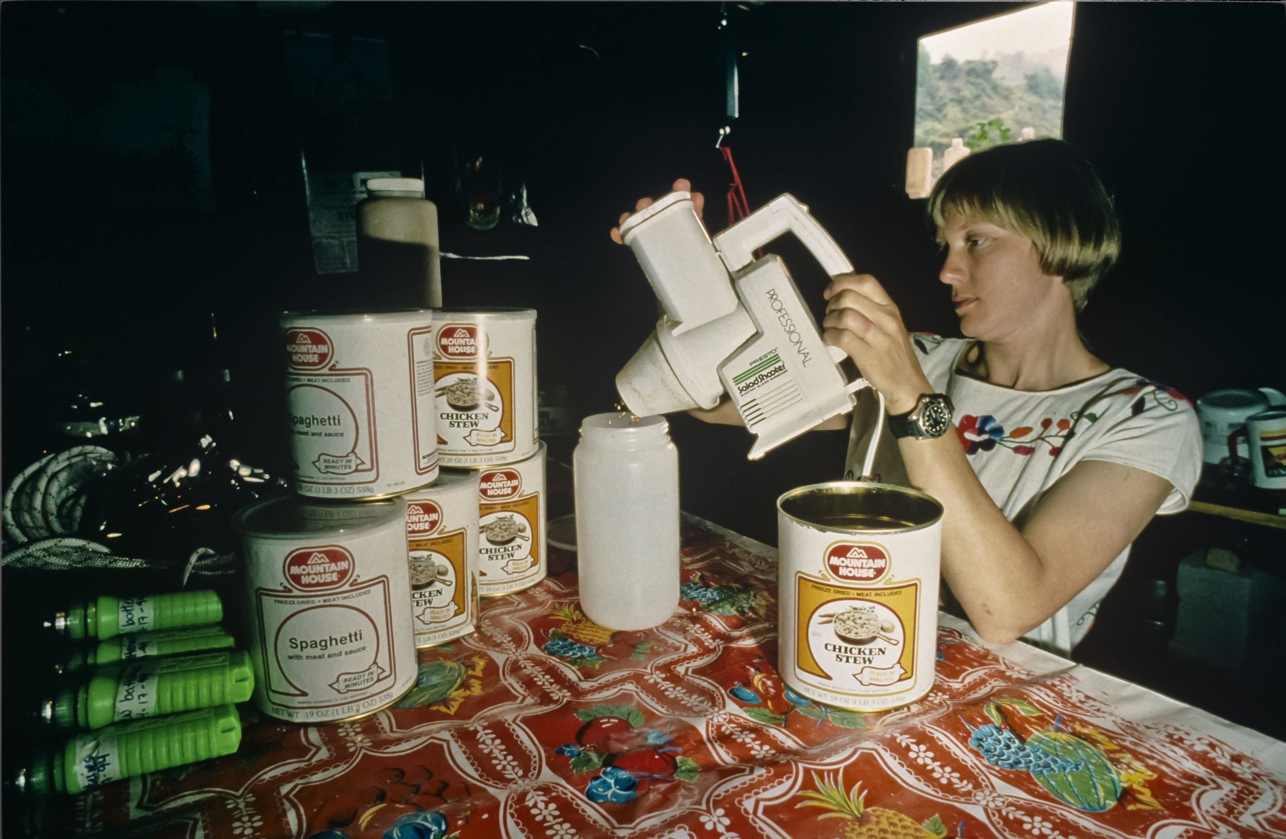  "Reducing perfectly good freeze dried food to dust" is Barbara am Ende's job, as she uses a "Salad Shooter" to aid in compressing food for the underground camps into Nalgene bottles. Photo by U. S. Deep Caving Team/Bill Stone. 