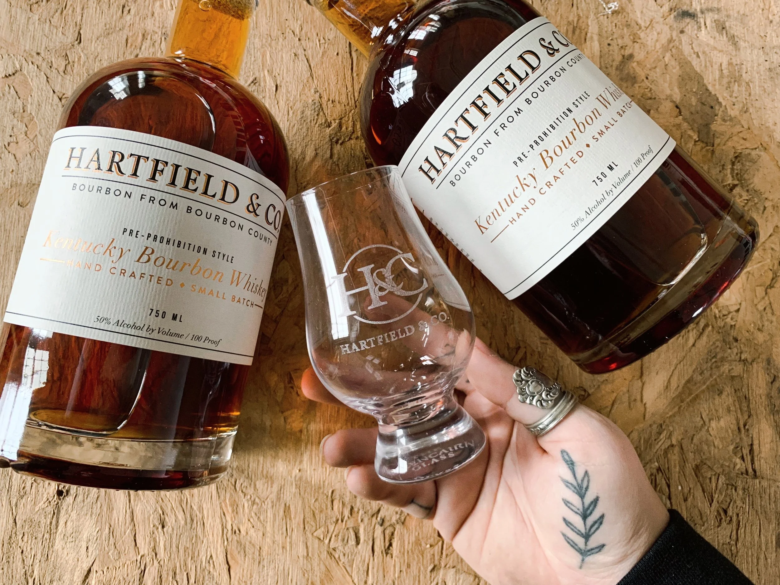 Hartfield & Co. Glencairn Whiskey Tasting Glass Next to Bottles - copyright Hartfield & Co. 2023 www.hartfieldandcompany.com