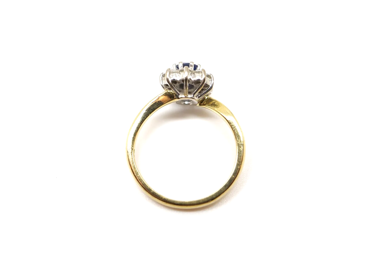 An 18ct gold sapphire and diamond cluster ring from 1998, set with an oval cut sapphire of approximately 0.6 carats at the centre, surrounded by ten round brilliant cut diamonds of 0.4 carats