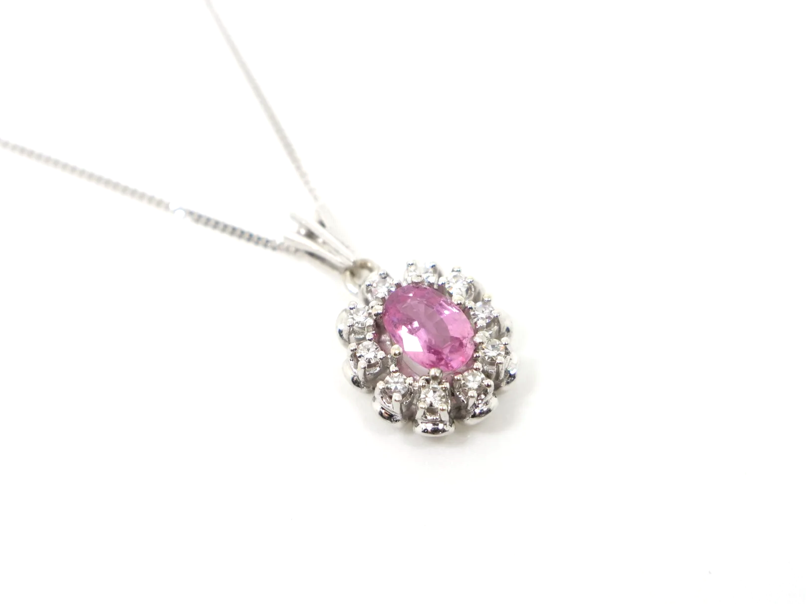 vintage 14ct white gold pink sapphire and diamond cluster pendant, set with a striking oval cut pink sapphire and surrounded by diamonds.