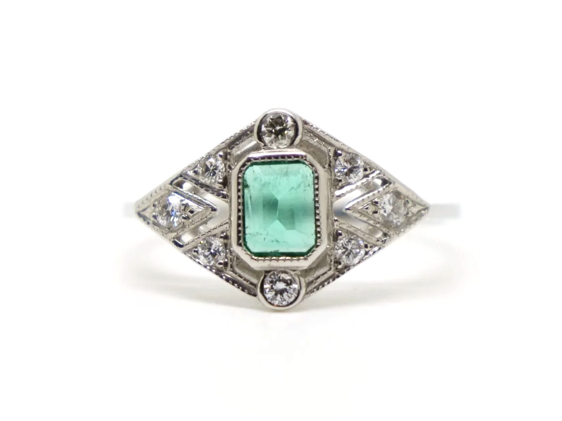 Lovely Art Deco style ring in platinum, set with an emerald cut emerald with emeralds set into this unusual geometric design.