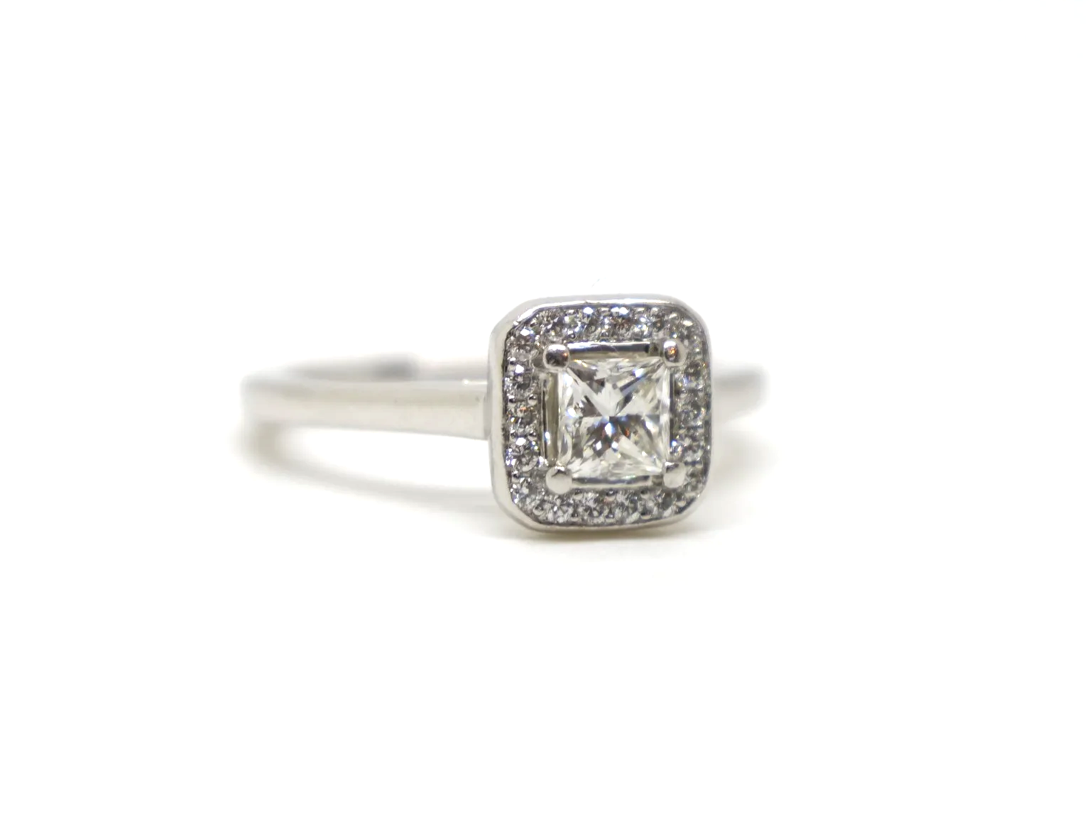 Beautiful platinum diamond ring, set with a central princess cut diamond of excellent quality and surrounded by a halo of diamonds.