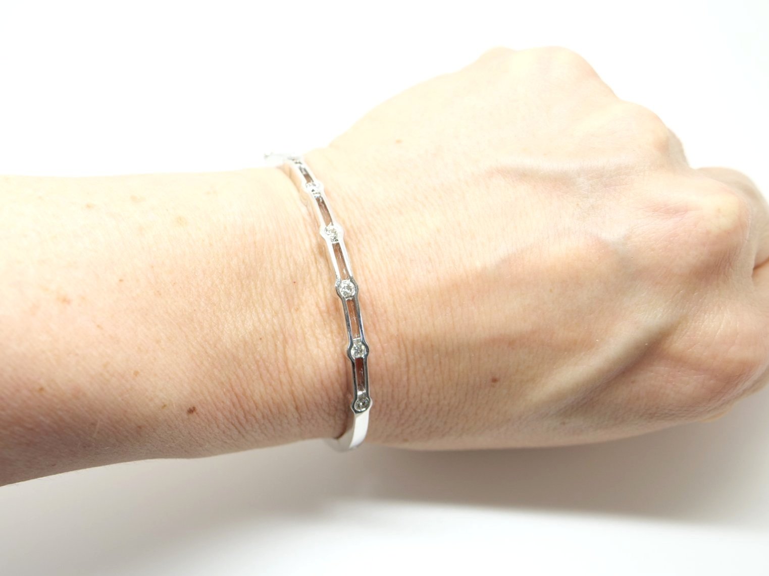 Lovely quality 9ct white gold bangle, set with six brilliant cut diamonds in this unusual design. Approximately 0.5ct diamond weight total. With safety catch.
