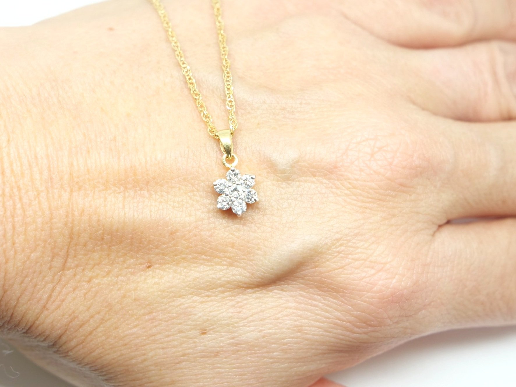 Classic 18ct gold diamond flower pendant, set with seven brilliant cut diamonds of 0.5cts. With pretty 9ct gold chain.