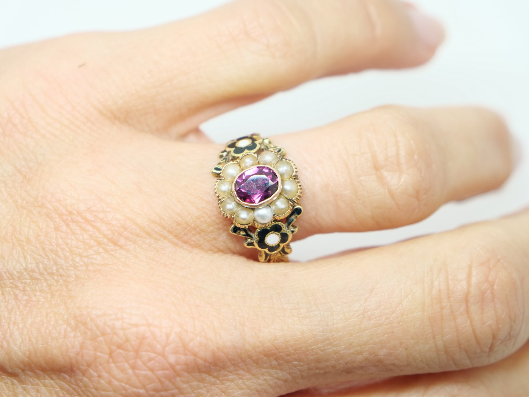 Lovely 18ct gold Georgian garnet and seed pearl ring, set with an oval cut garnet and surrounded by seed pearls. Black enamel flower design to each shoulder.