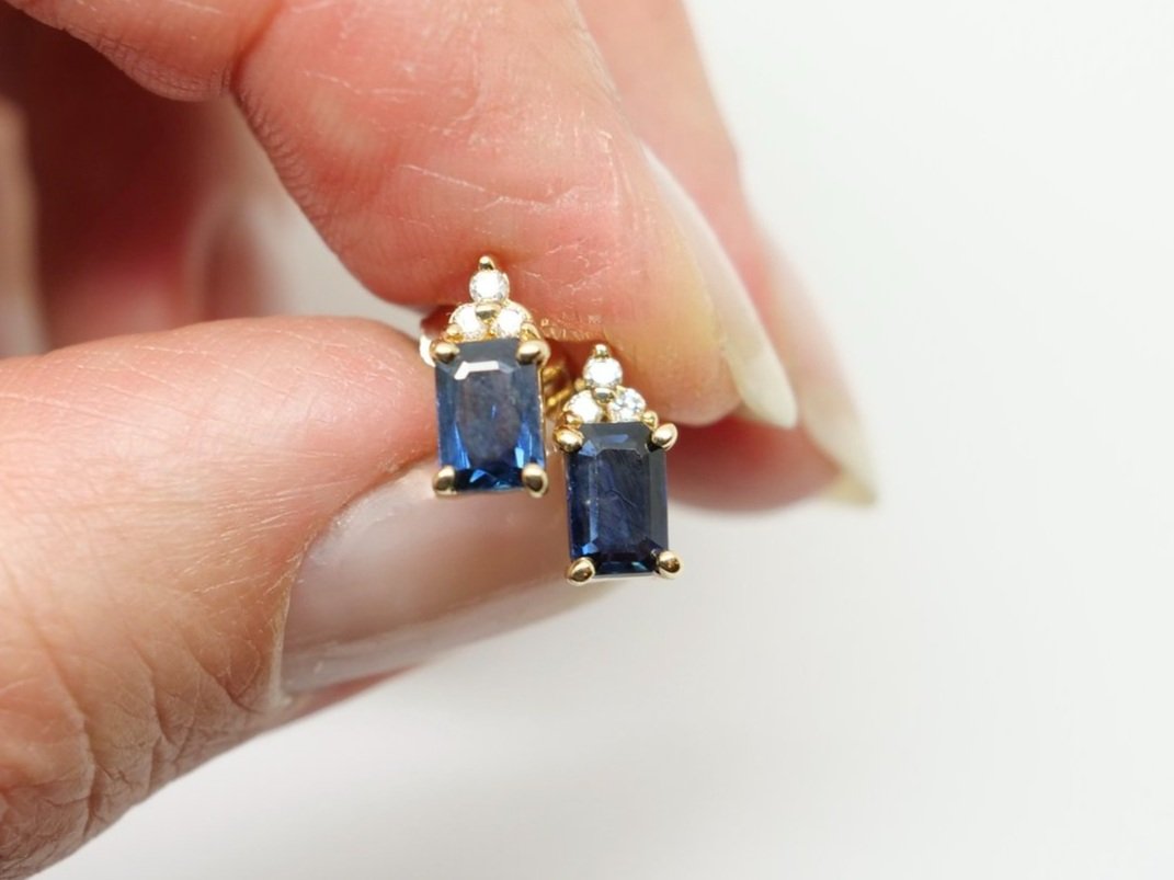 Lovely 14ct gold sapphire and diamond earrings, each set with an emerald cut blue sapphire, with three small diamonds above.