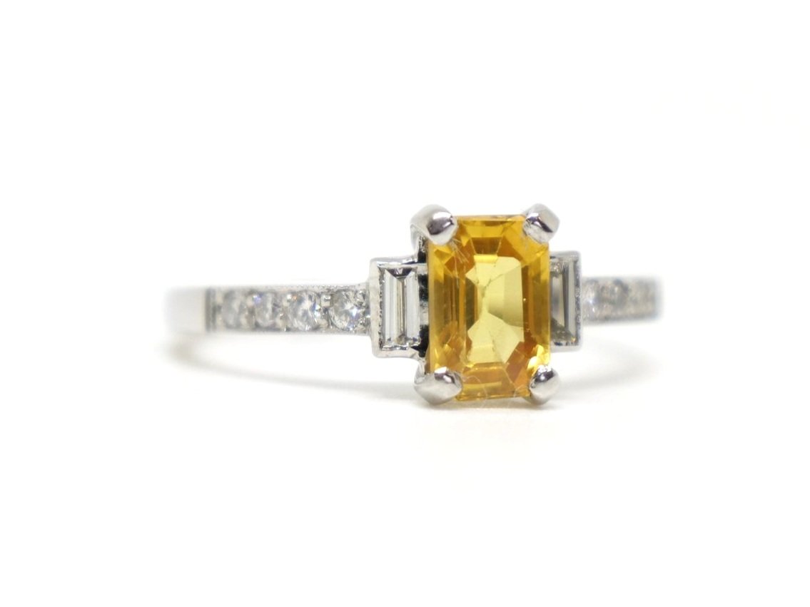 Beautiful vintage style platinum yellow sapphire and diamond ring, set with a 1ct emerald cut sapphire with a baguette cut diamond to each side. Further diamonds to each shoulder.