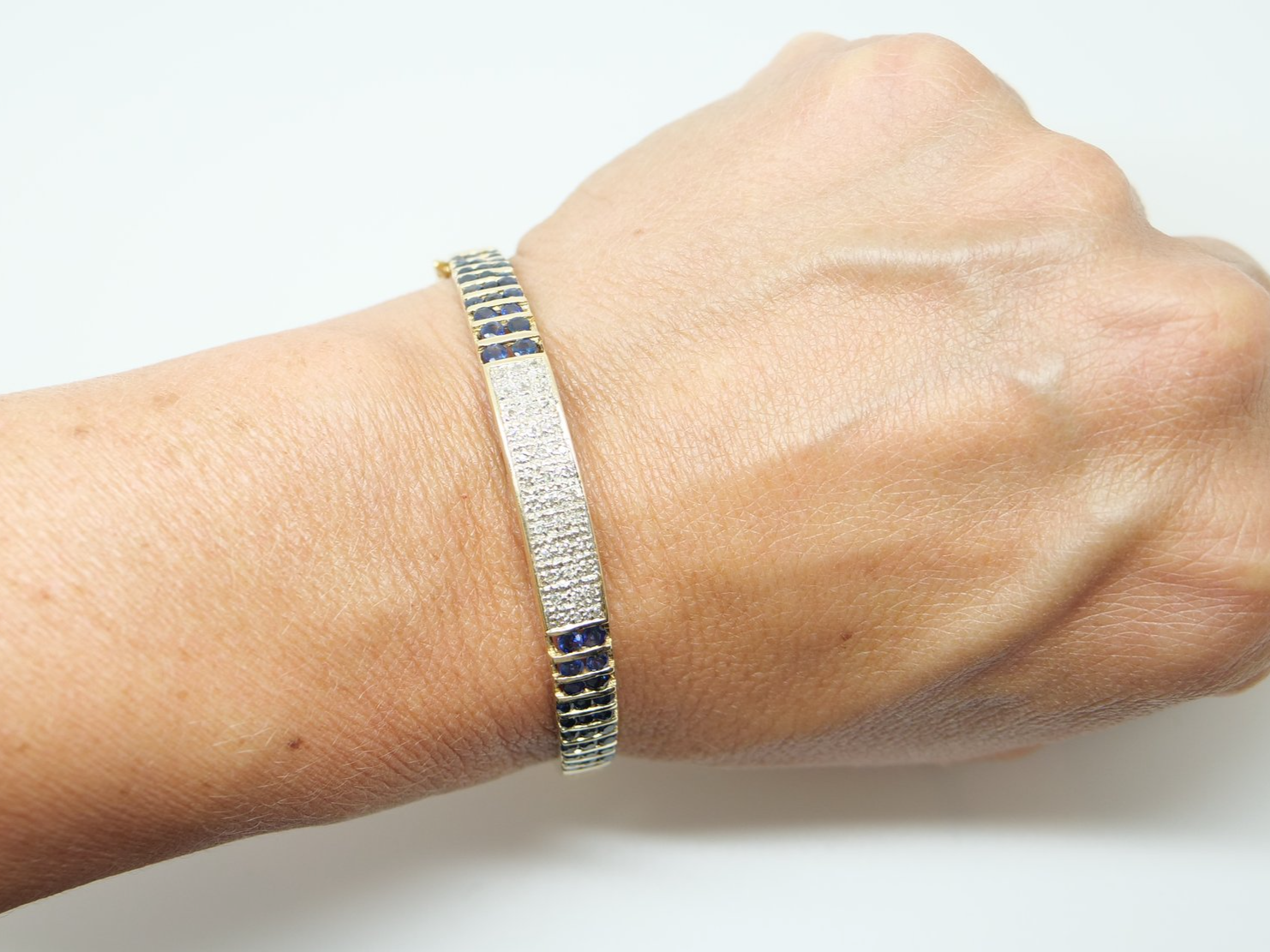 Unusual vintage 9ct gold sapphire and diamond bangle, set with a pave design central panel set with diamonds, with channel set sapphires to each side.