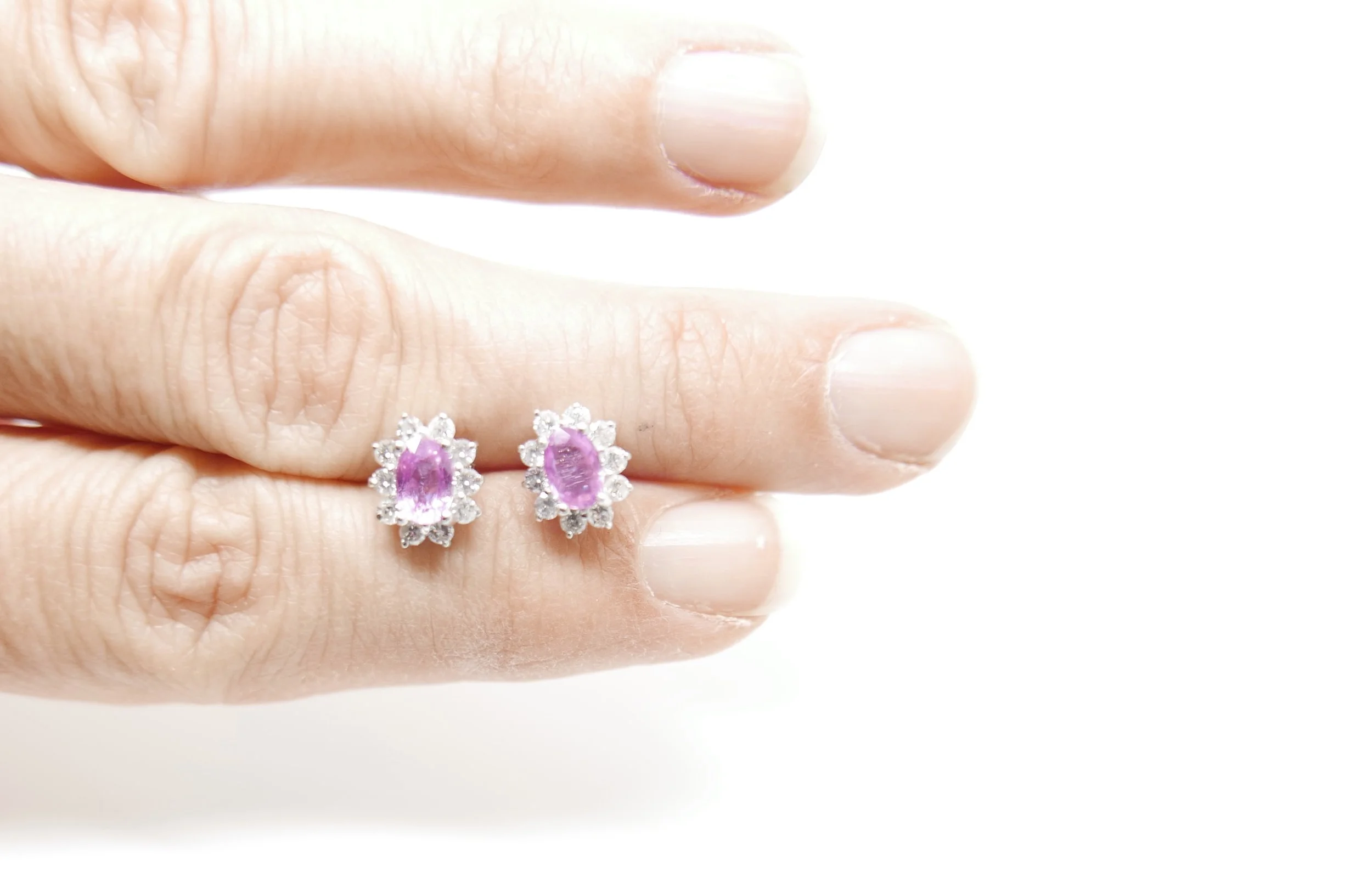pink sapphire and diamond stud earrings, set with oval cut pink sapphires, surrounded by diamonds. Approximate diamond weight of 0.5cts. Stamped 750 for 18ct white gold.