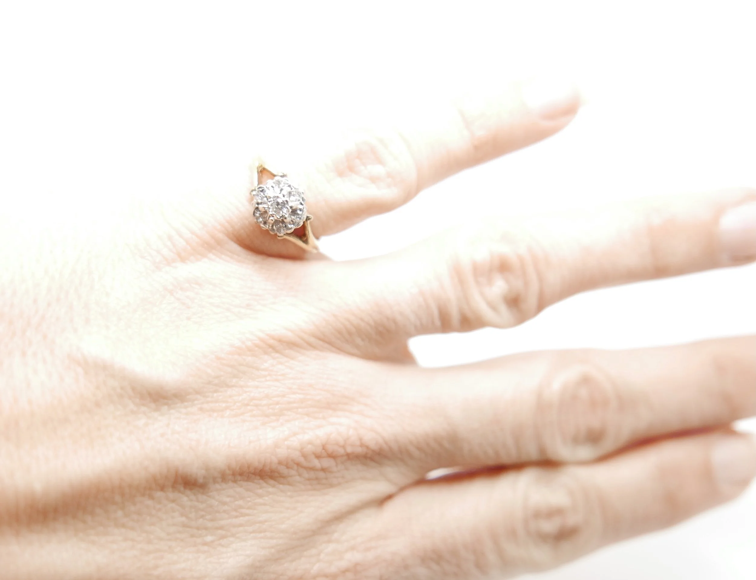 Sparkly vintage ring in 18ct gold, set with a central brilliant cut diamond, with six smaller diamonds in this classic cluster design.