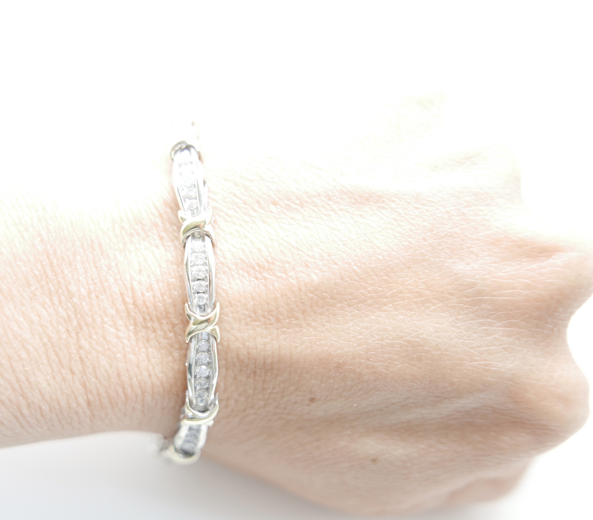 Lovely diamond tennis bracelet, set with approximately sixty brilliant cut diamonds with a yellow gold criss cross design. All set in 10ct gold.