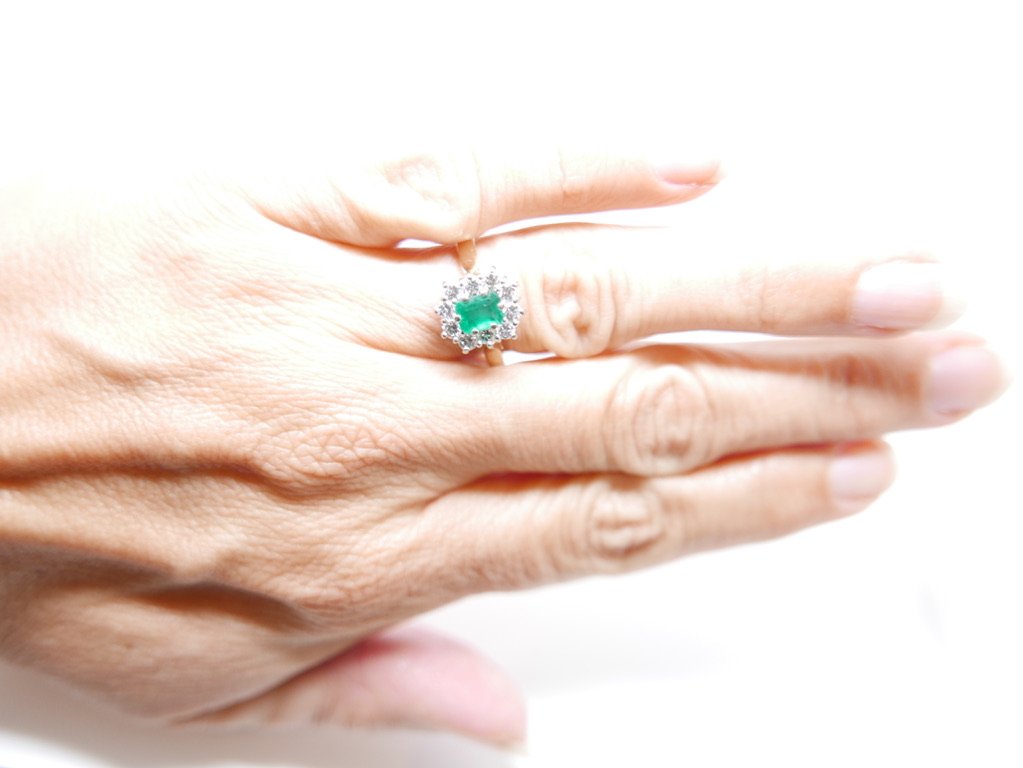 Classic emerald cut emerald and diamond ring, set with a central emerald cut emerald of 0.65ct, surrounded by 0.6ct diamonds in an unusual rectangular design. All set in 18ct gold.