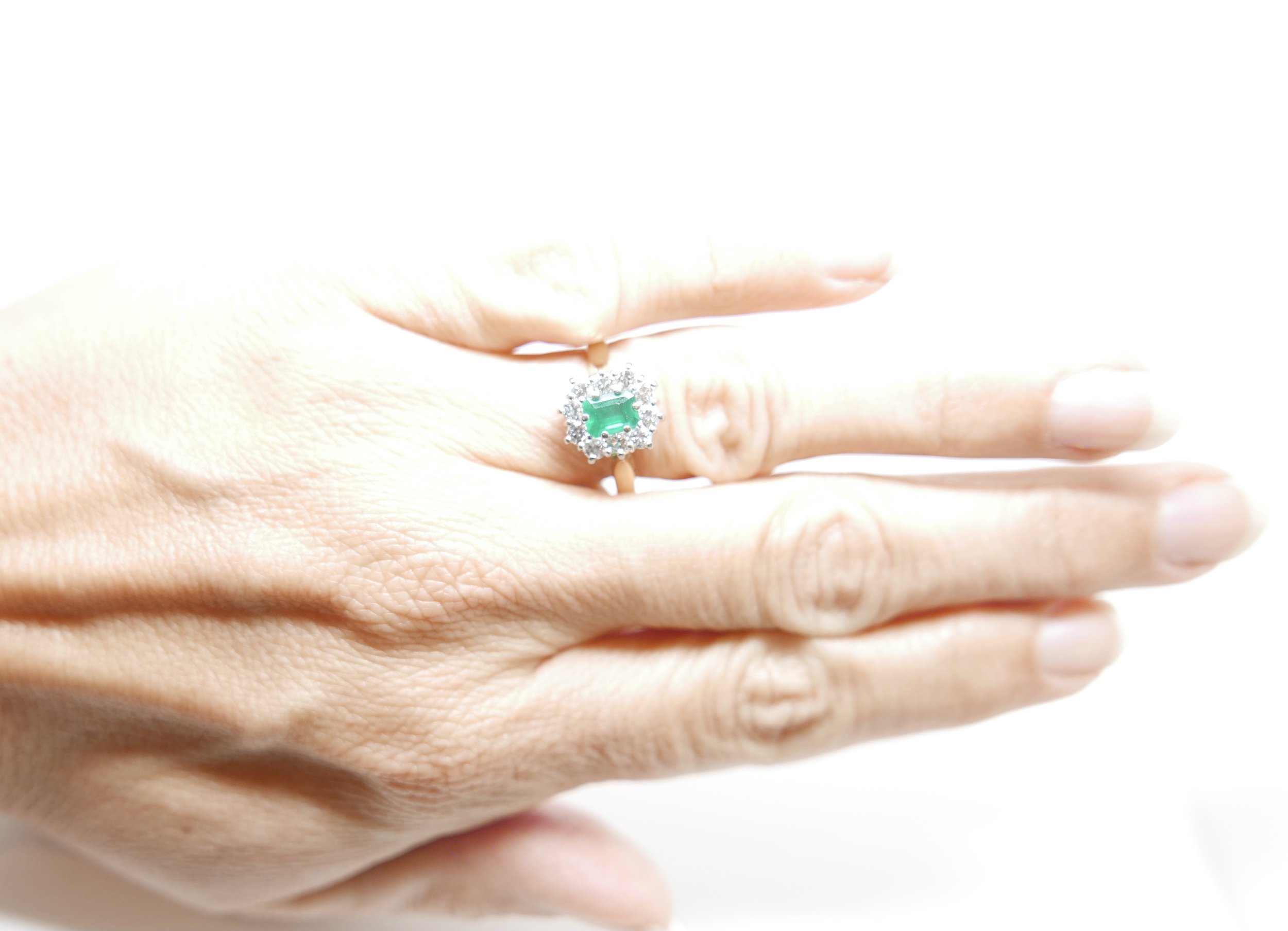Classic emerald cut emerald and diamond ring, set with a central emerald cut emerald of 0.65ct, surrounded by 0.6ct diamonds in an unusual rectangular design. All set in 18ct gold.