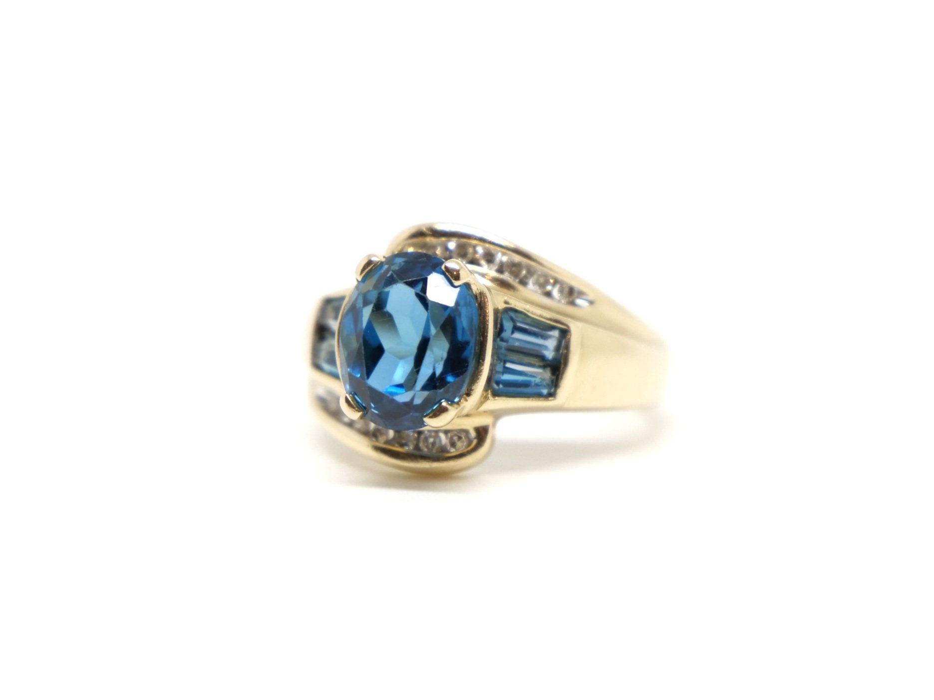 Very unusual 14ct gold blue topaz and diamond cocktail ring, set with a central oval cut blue topaz and baguette cut topaz to each shoulder. Further small diamonds both above and below.
