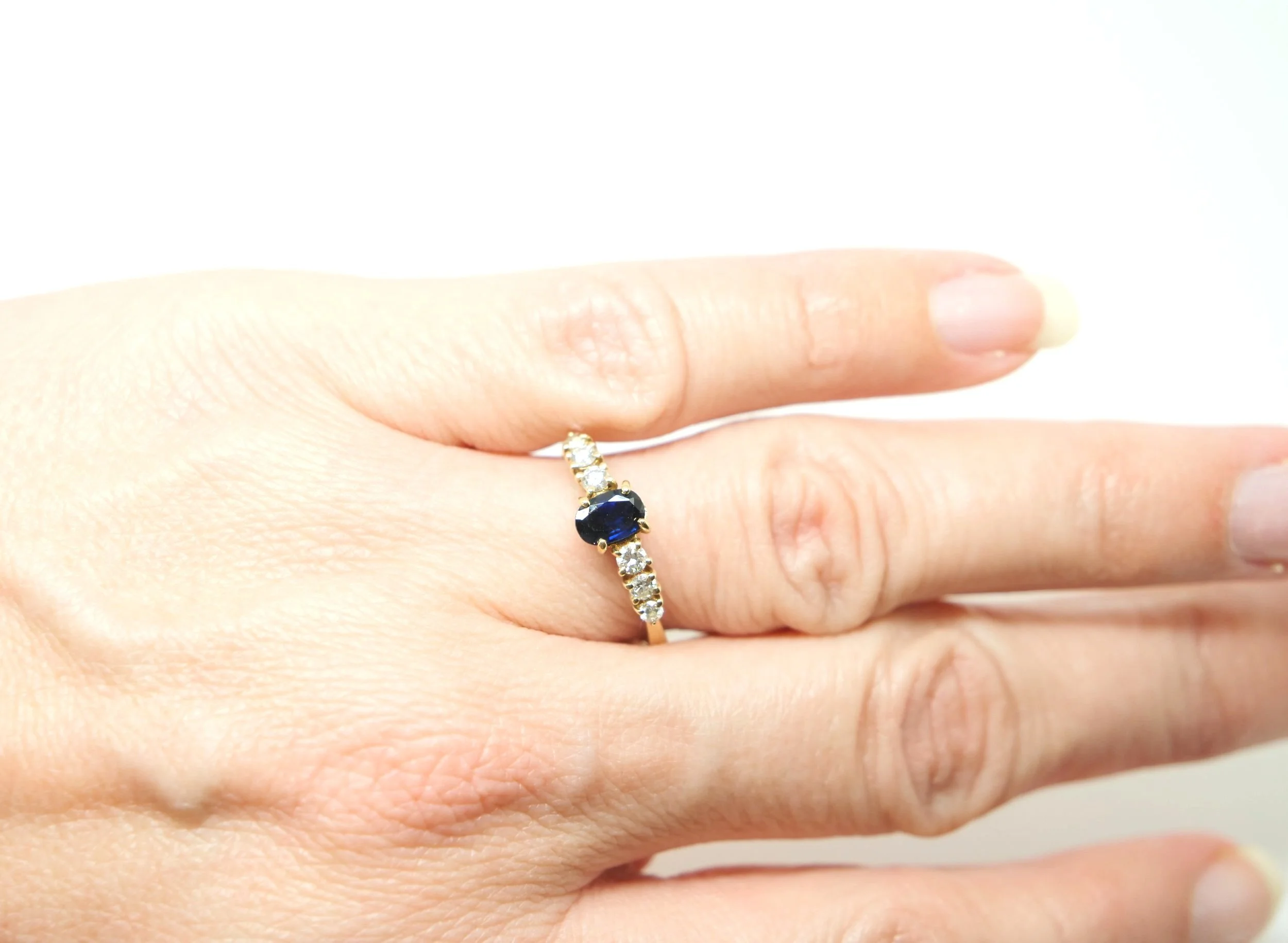 Very pretty 18ct gold sapphire and diamond ring, set with a central oval cut sapphire of approximately 0.6cts. Three brilliant cut diamonds to each side.
