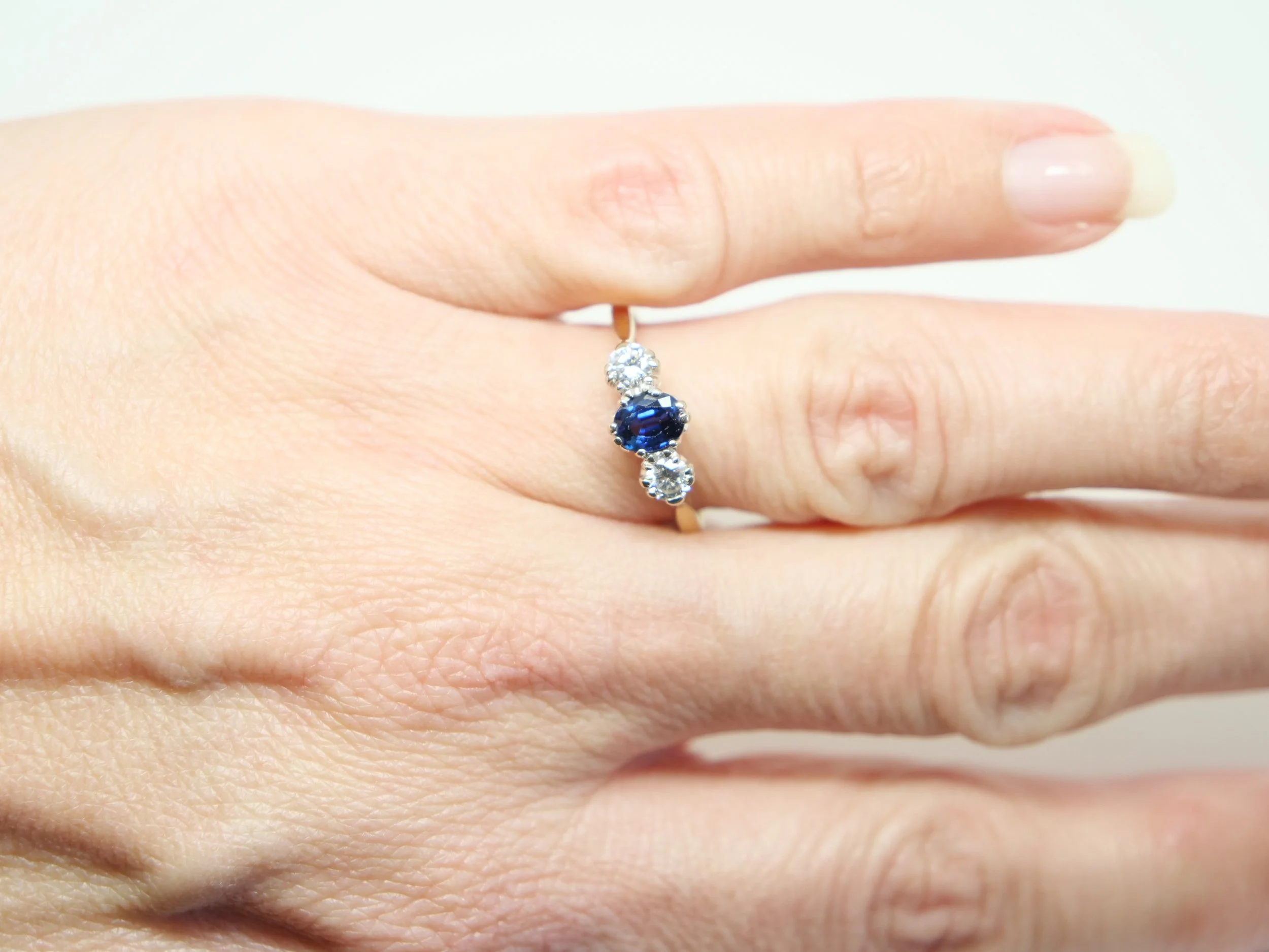 Lovely vintage sapphire and diamond trilogy ring, set with a central oval cut mid blue sapphire of approximately 0.55cts. A brilliant cut diamond to each side, approximately 0.32cts, in 18ct gold.