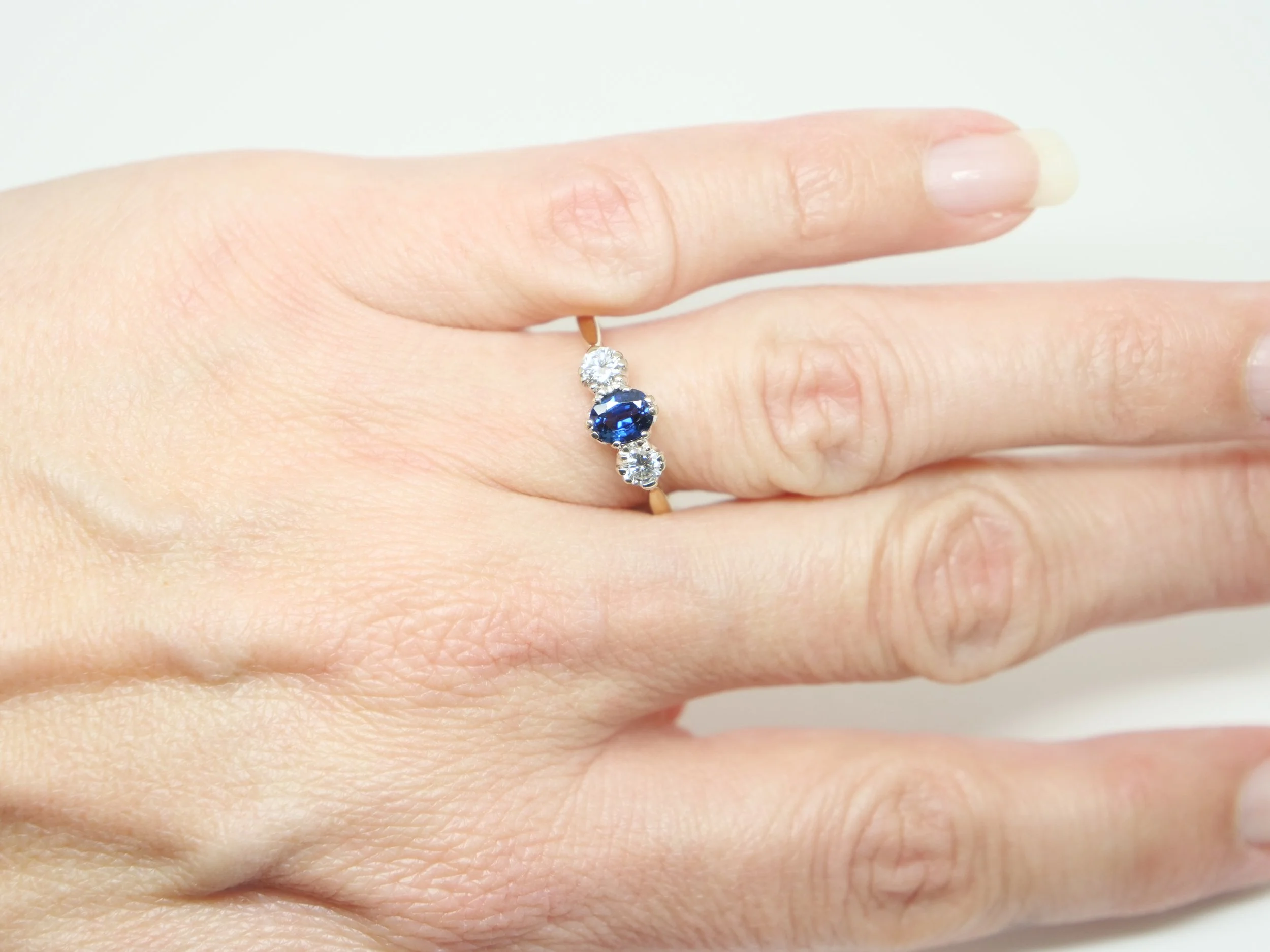 Lovely vintage sapphire and diamond trilogy ring, set with a central oval cut mid blue sapphire of approximately 0.55cts. A brilliant cut diamond to each side, approximately 0.32cts, in 18ct gold.