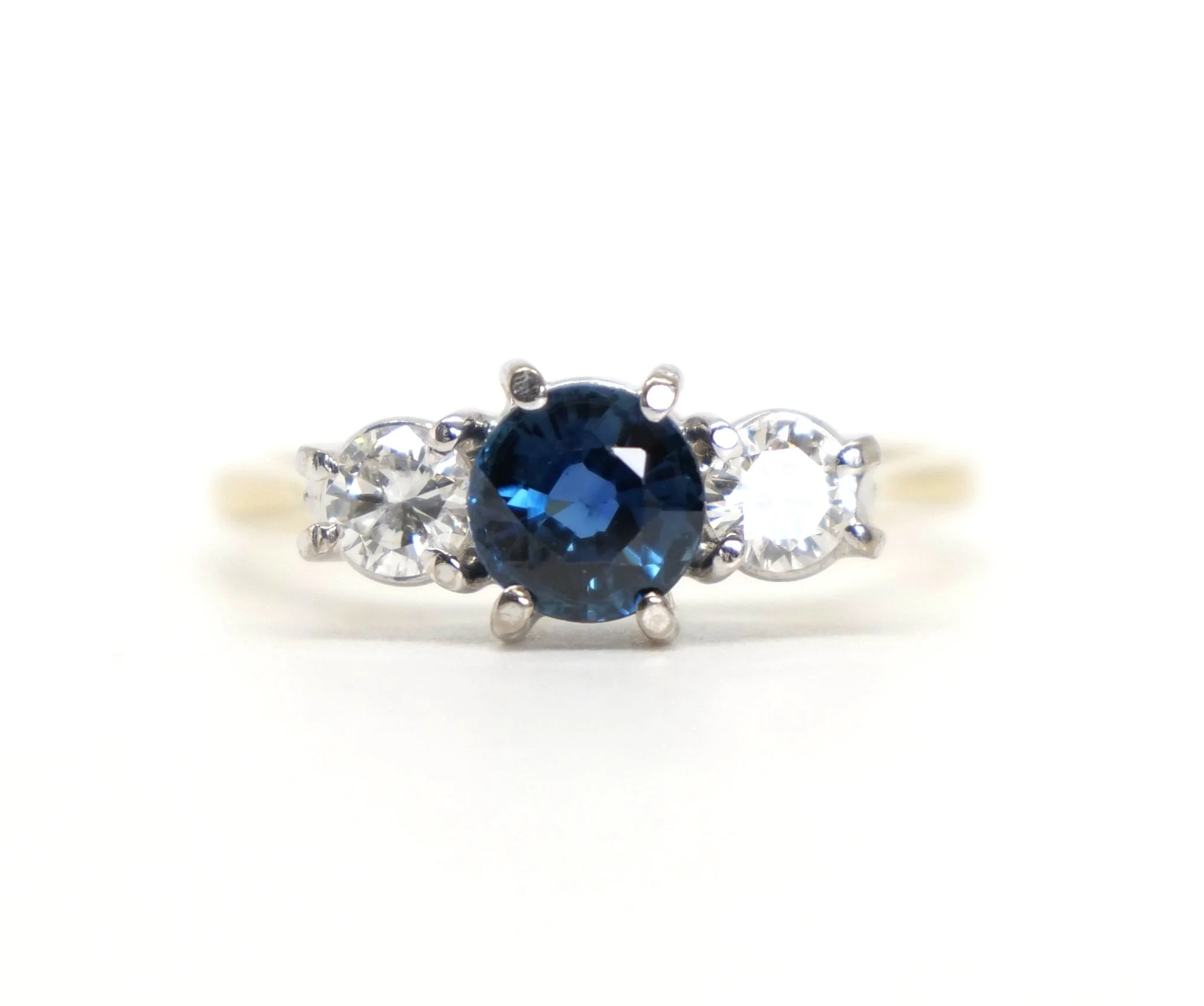 Classic 18ct gold vintage sapphire and diamond trilogy ring, set with a beautiful blue round cut central sapphire of approximately 0.7ct, with a brilliant cut diamond to each side.