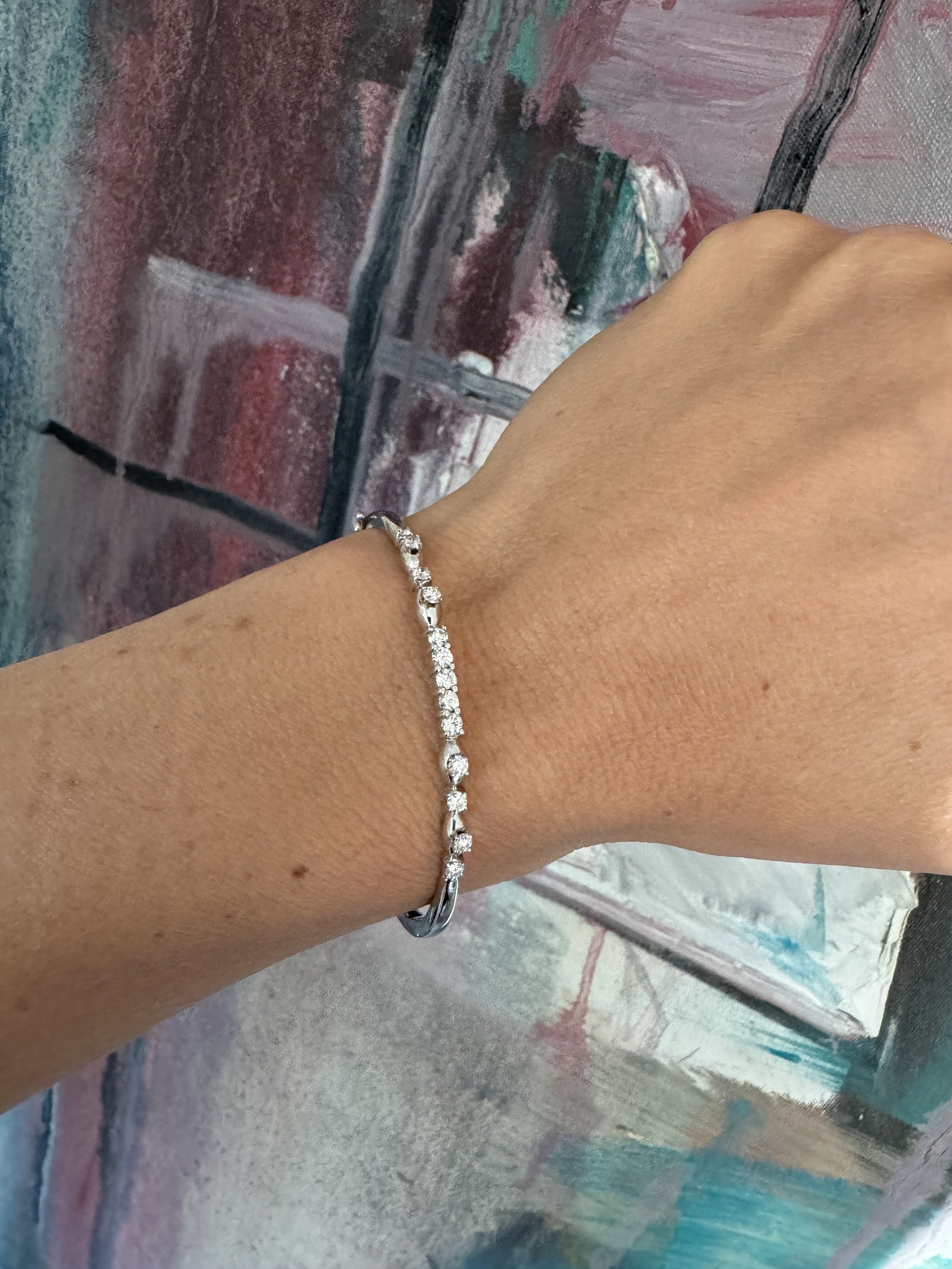 Lovely 18ct white gold bangle, set with thirteen brilliant cut diamonds, with an approximate diamond weight of 0.6cts. Double figure of eight safety clasps.