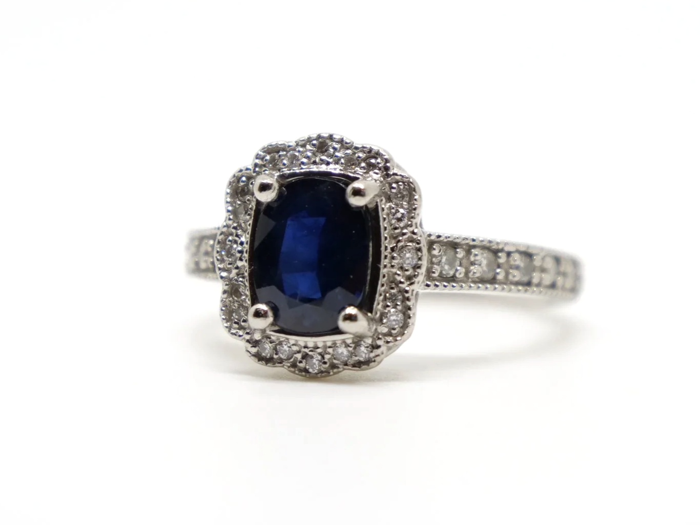 Lovely vintage design platinum ring, set with a large oval cut sapphire and surrounded by diamonds. Further diamonds set into each shoulder.
