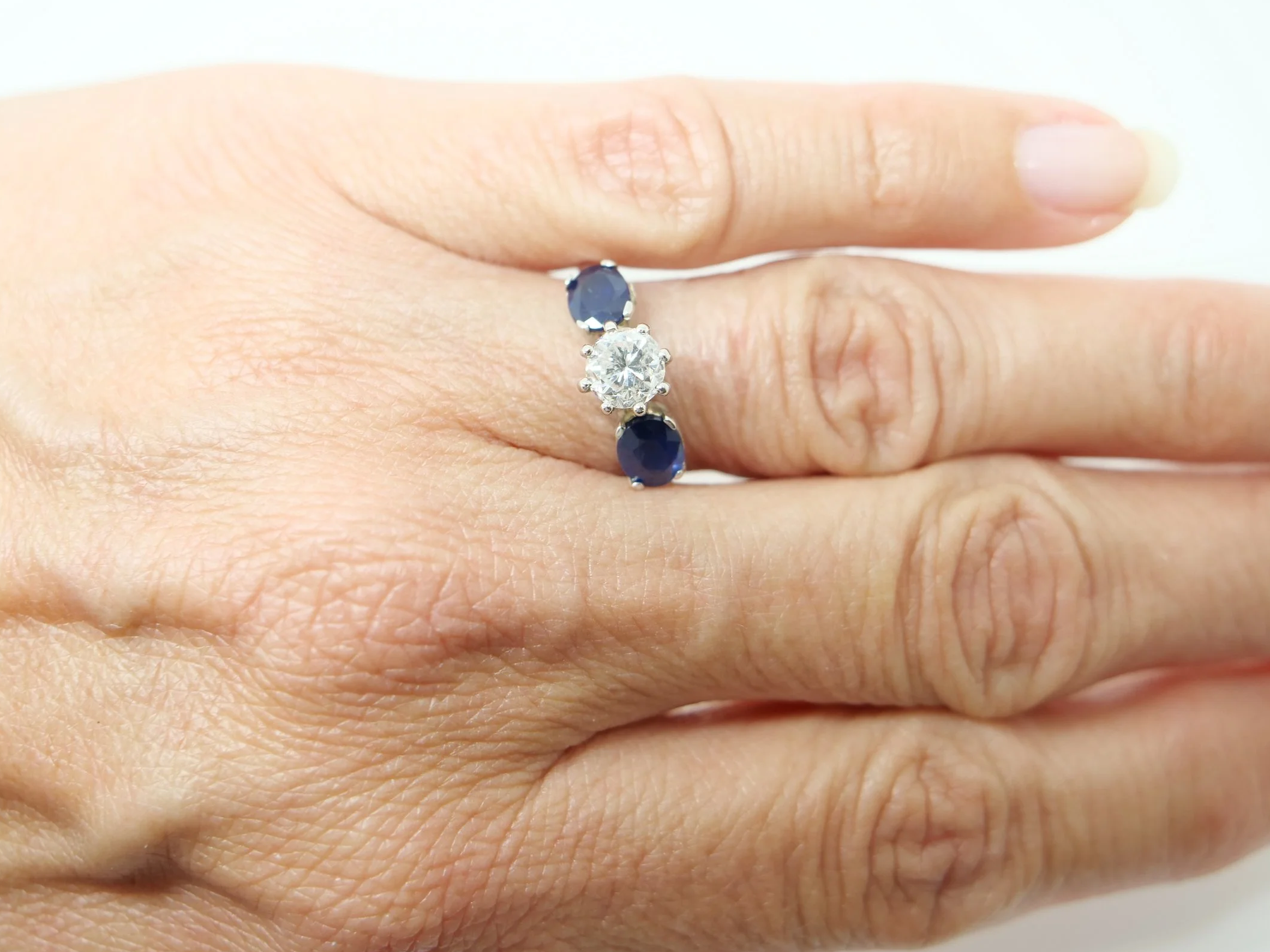 unusual vintage three stone ring in 18ct white gold with a round old cut diamond of approximately 1 carat at the centre, flanked by two oval cut sapphires of approximately 1.4 carats in total.