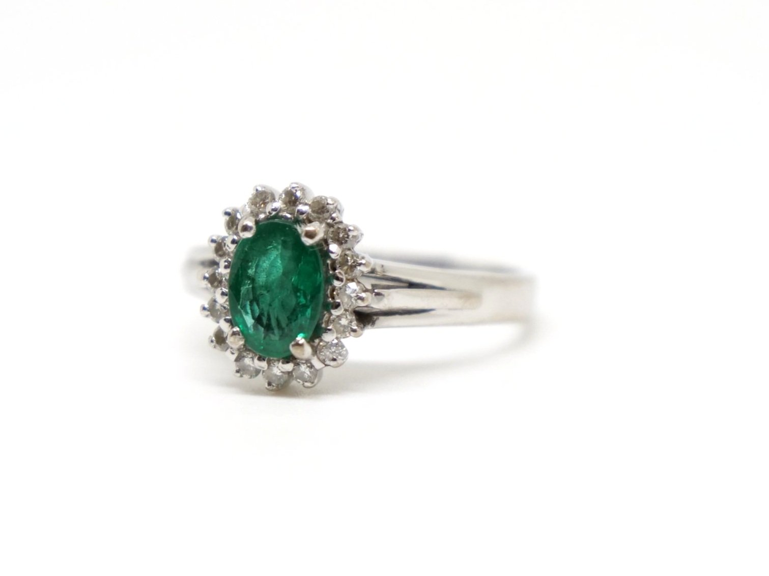 Classic 18ct gold vintage emerald and diamond cluster ring, set with a central oval cut emerald of approximately 0.75ct, surrounded by ten diamonds.