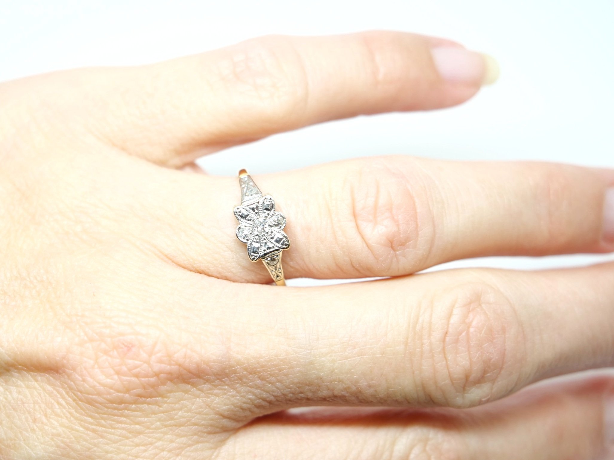 Very pretty 18ct gold Art deco diamond ring, in an unusual floral bow design and set with three small central diamonds. A further diamond set to each shoulder.
