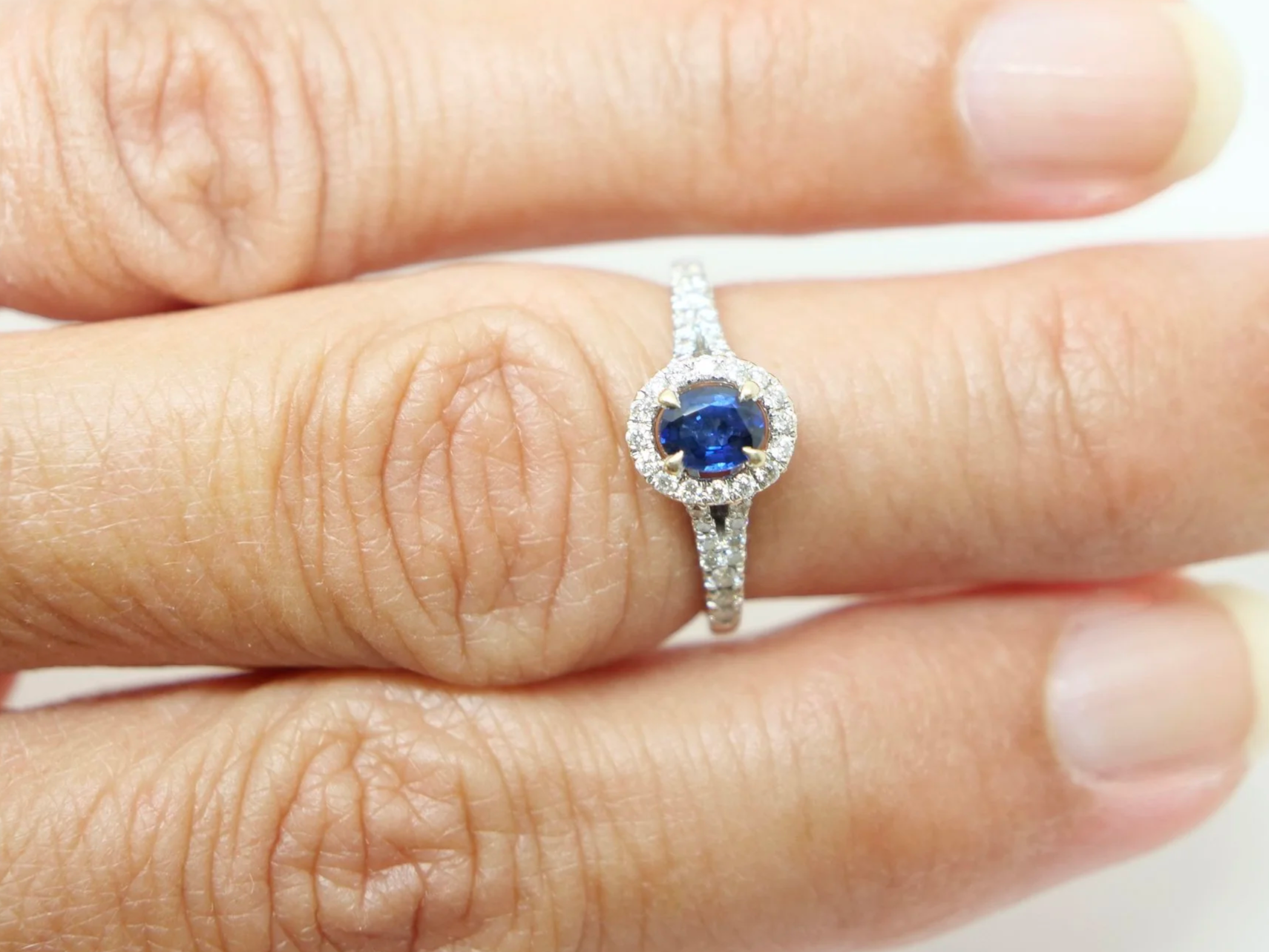 Very pretty 18ct gold sapphire and diamond ring, set with an oval cut sapphire and surrounded by diamonds. With split shank diamond shoulders.