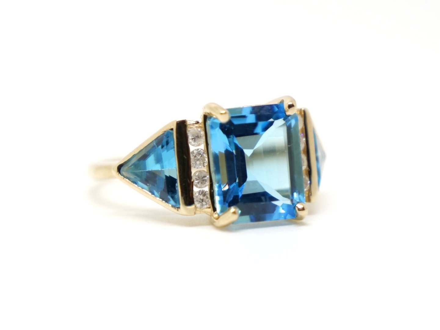 Super 14ct gold blue topaz and diamond cocktail ring, set with an emerald cut and two trillion cut bright blue topaz stones, with small diamonds set between.