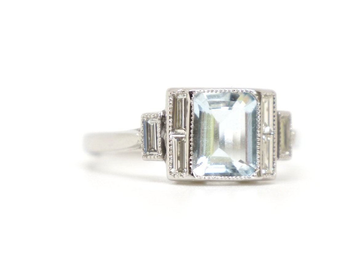 Art Deco style platinum aquamarine and diamond ring, set with a central emerald cut aquamarine, with baguette cut diamonds to each shoulder.