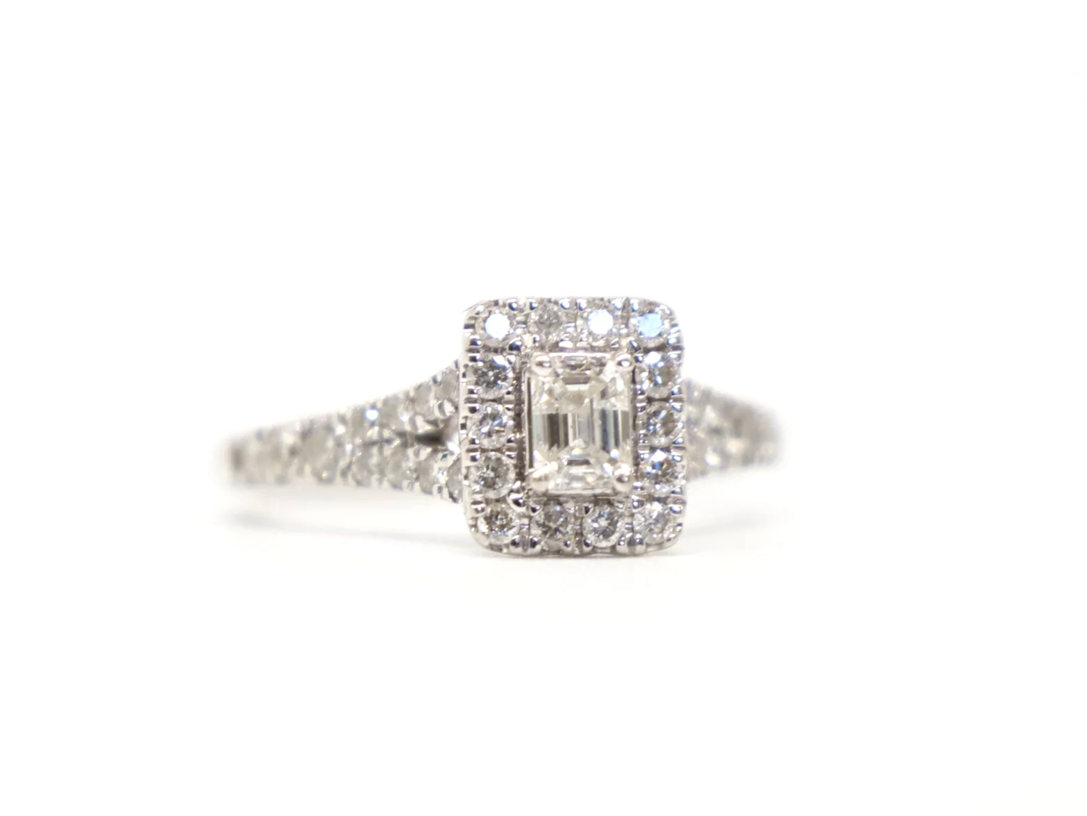 platinum diamond cluster ring set with an emerald-cut diamond at the centre, surrounded by a rectangular pavé-set halo of round brilliant-cut diamonds